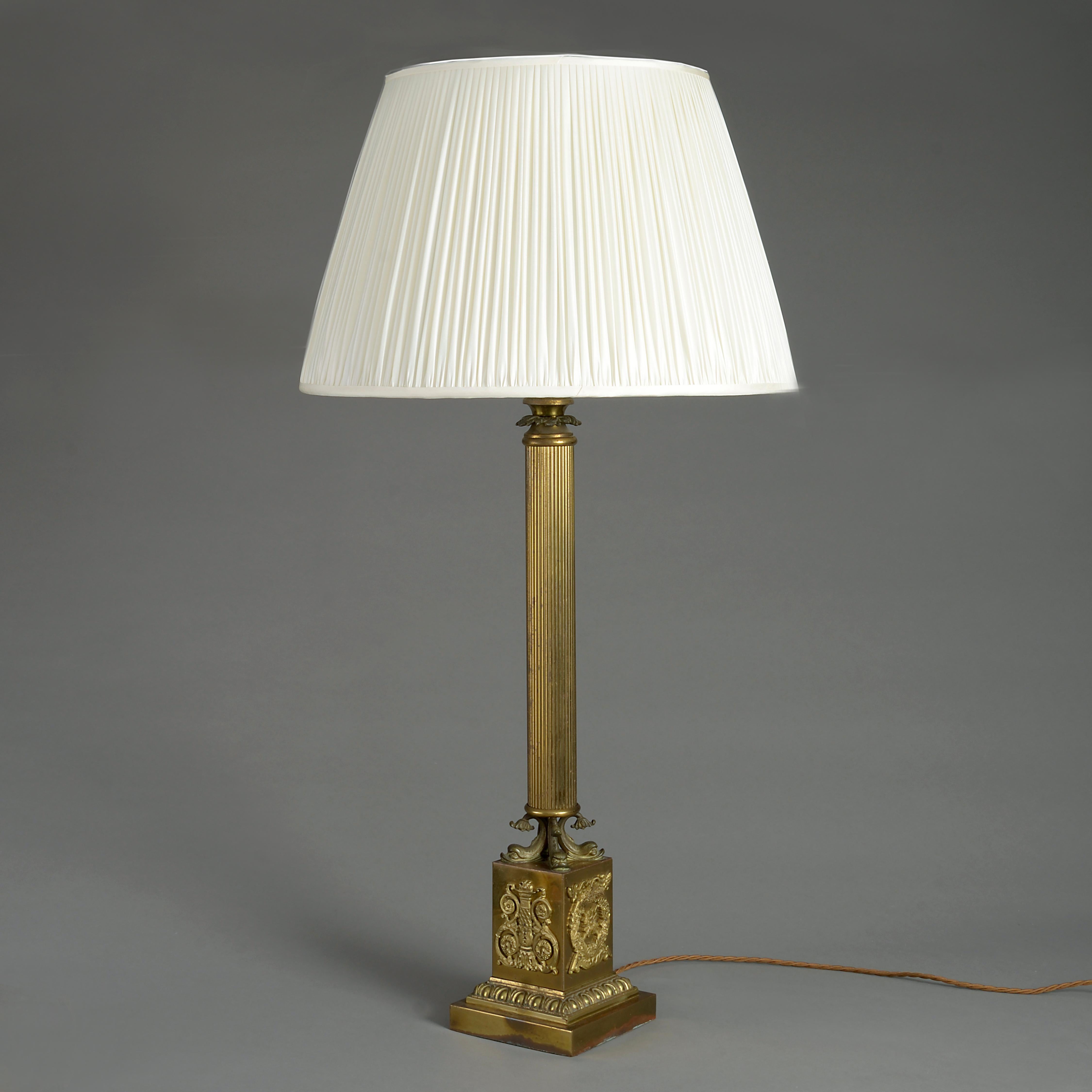 An early 19th century Empire Period gilt brass column lamp, the fluted column set upon a plinth with stylised dolphin supports.