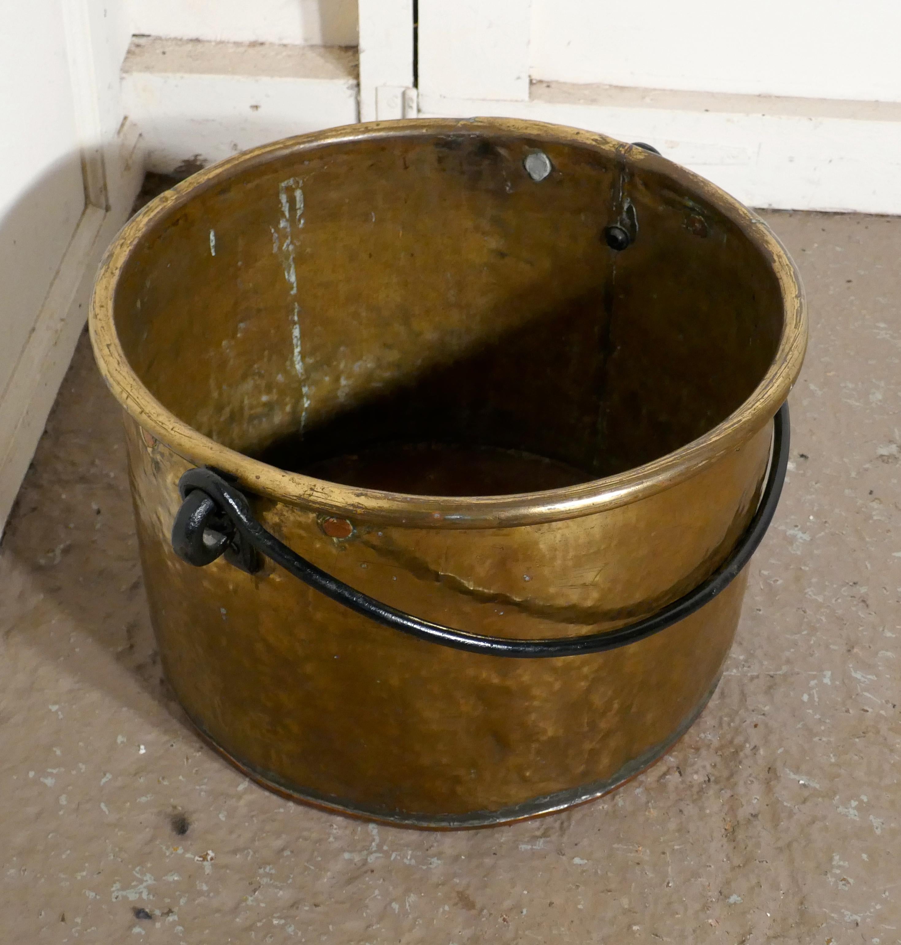 Early 19th century brass cooking pot

This is a lovely cooking 19th century cooking pot, (or coal/log bucket)
The pot has a rolled top and the Iron handle swings through 180 degrees
The bucket has a replaced copper bottom and the handle also has