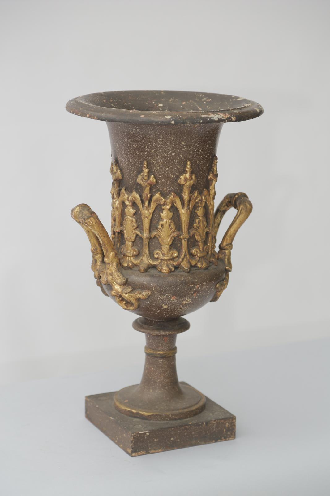Grand Tour urn, of bronze, with a gilt and patented finish showing natural wear, having a column-snape urn-form; its down-turned bezel over its body, decorated with an anthemion frieze of classical palmettes, raised on an knopped-hourglass neck,