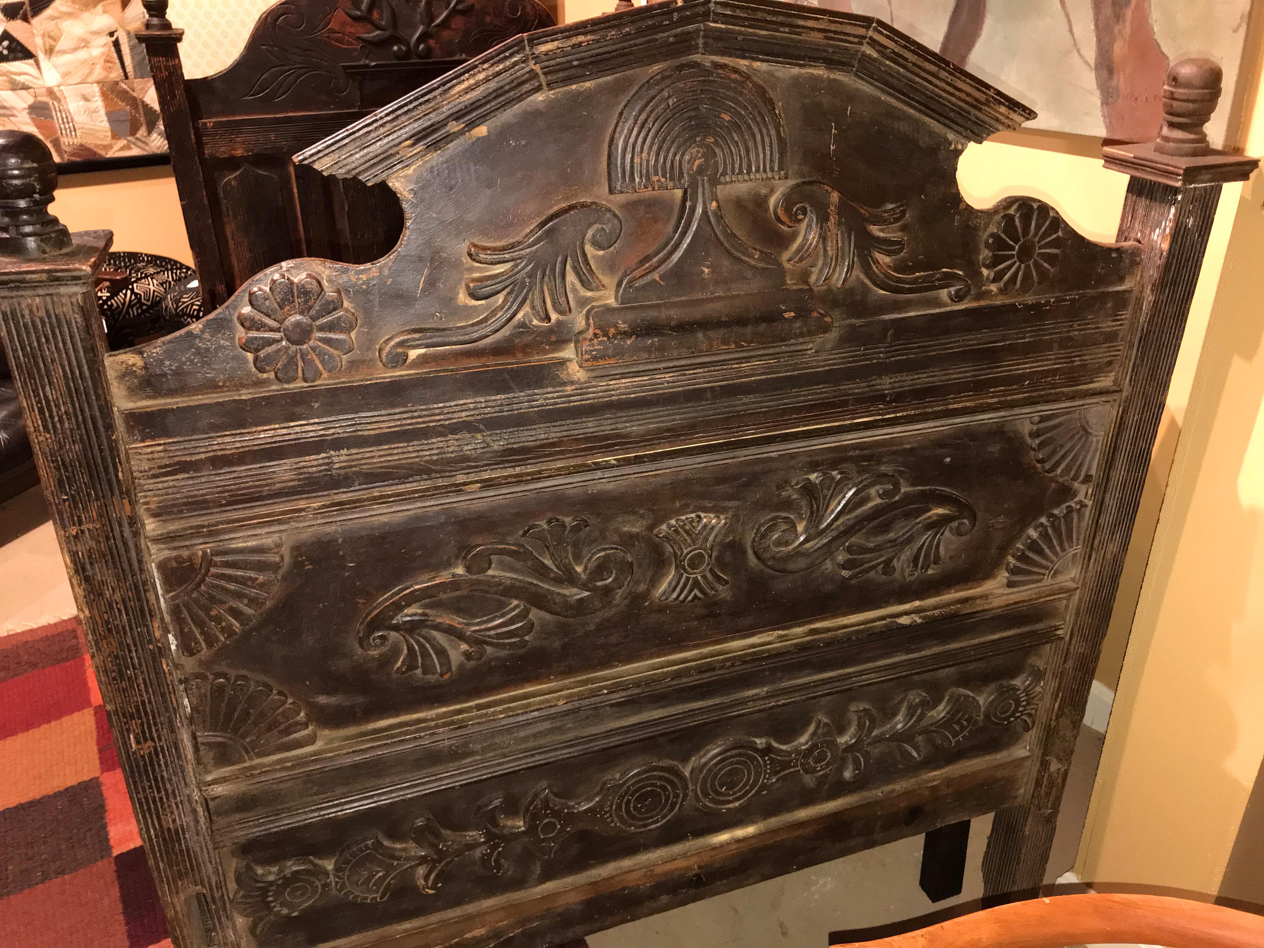 This early 19th century carved wooden bed, probably Guatemalan in origin, features a broken pediment headboard with carved dove and olive branches above small reeded panels, a footboard with decorative architectural fan and foliate carvings and