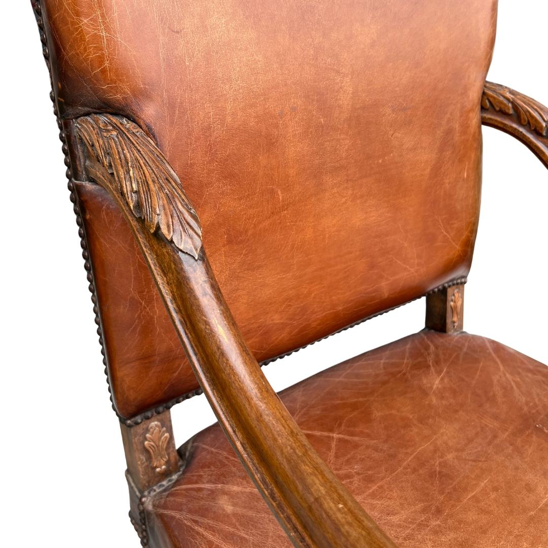 Circa early 19th Century England.

This chair is a true work-of-art and guaranteed to catch every eye in the room. 

Characterized by its tall back and curved arms, the chair is upholstered in a rich, brown leather, which is now time worn to a fine