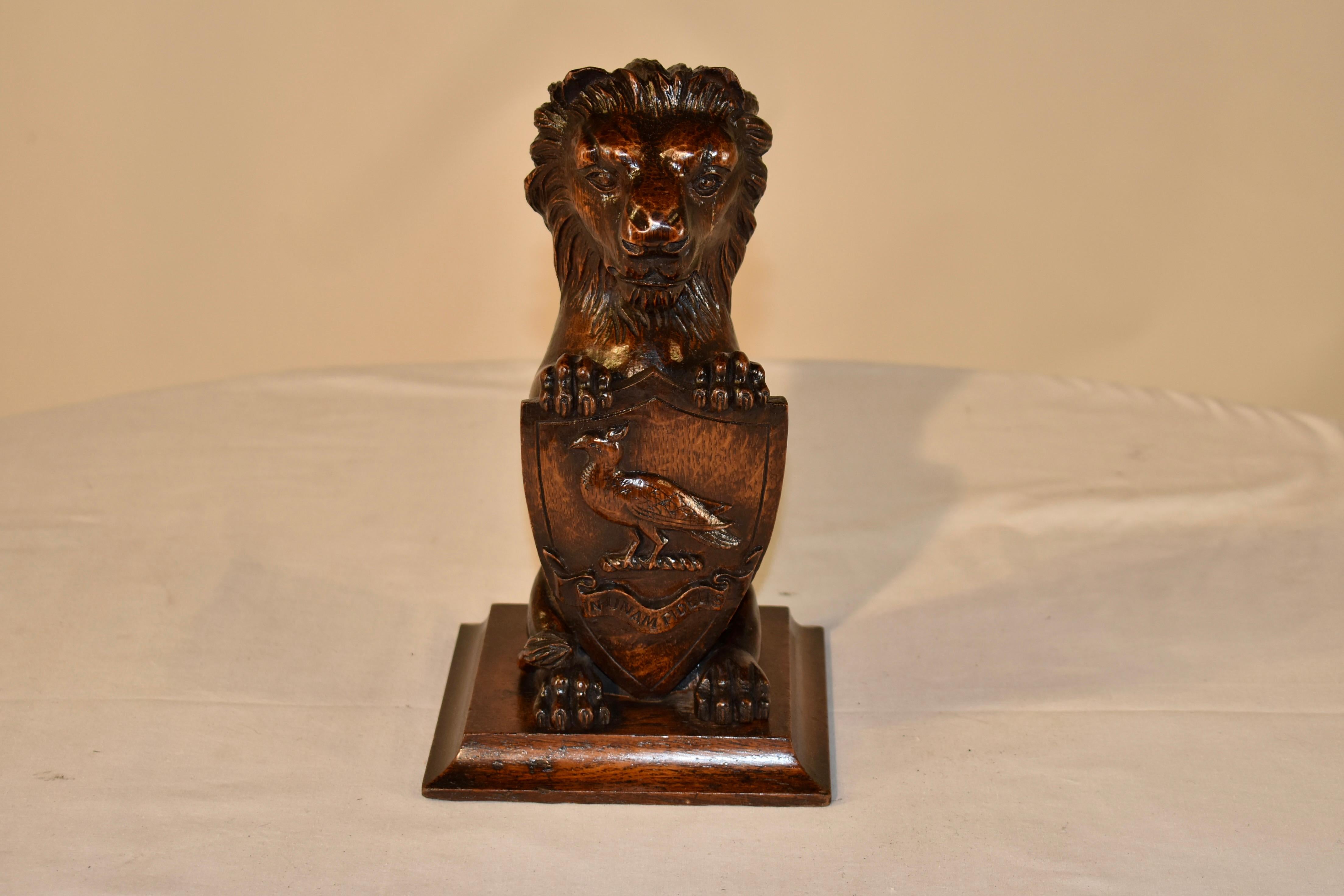 Early 19th century hand carved figure of a lion holding a shield. The shield has a single bird over a carved ribbon with the phrase 