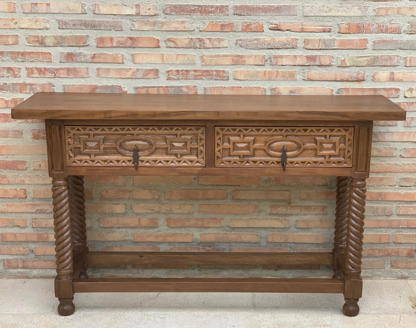 A 19th century walnut console table with a slab top above a frieze with two drawers with front decorated with carved geometrical motifs and incised with additional decoration and a single iron pull in each drawer. The table is supported on a hand