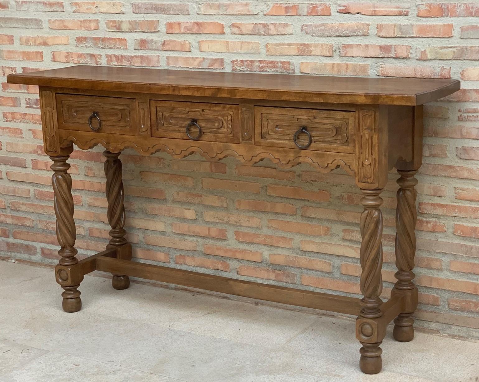 A 19th century walnut console table with a slab top above a frieze with three drawers with front decorated with carved geometrical motifs and incised with additional decoration and a single original iron pull in each drawer. The table is supported