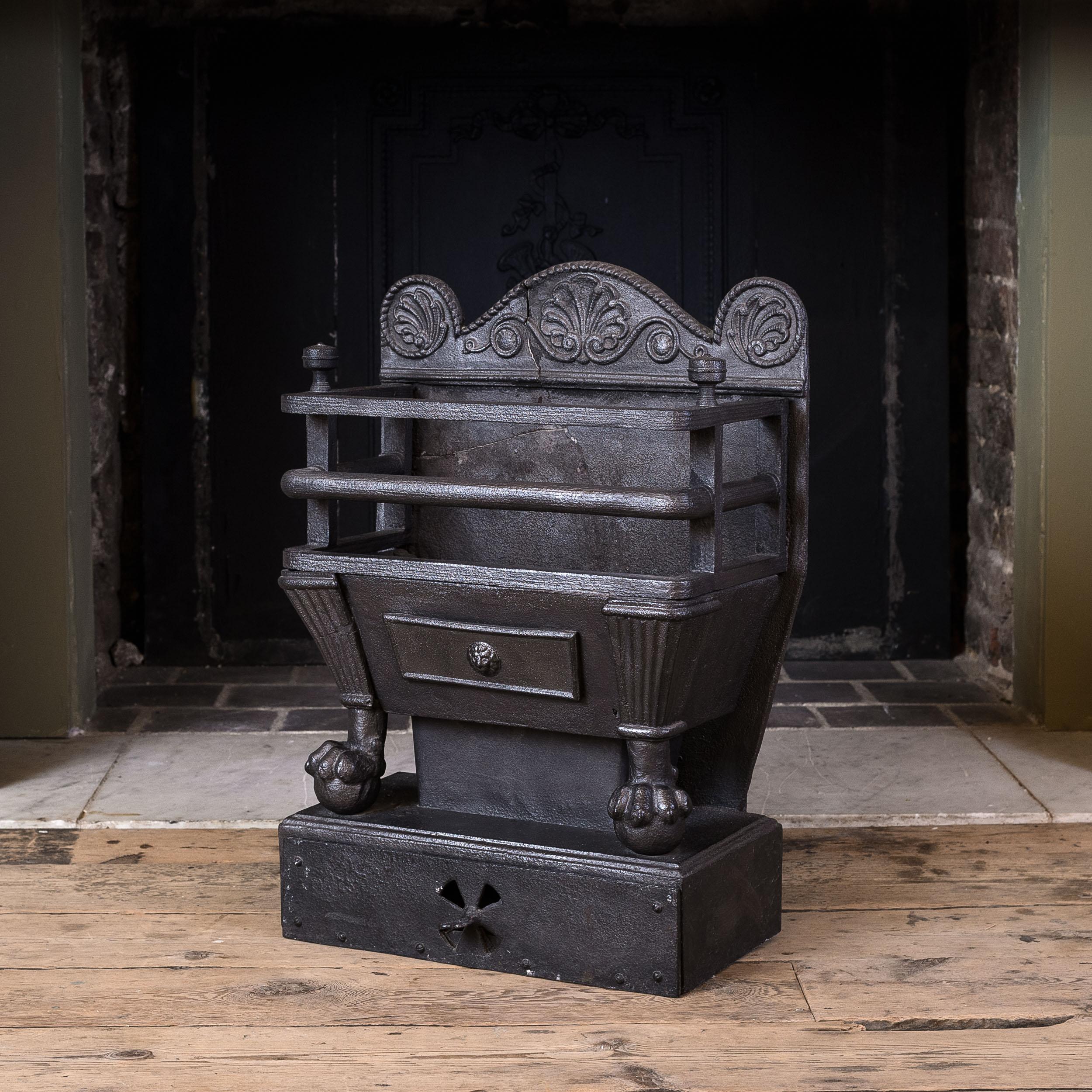 Early nineteenth century cast iron coal grate, c.1800, the shaped back-plate centred by anthemion, the reeded and railed basket with finials to either side and raised on ball and claw feet, all on plinth base.