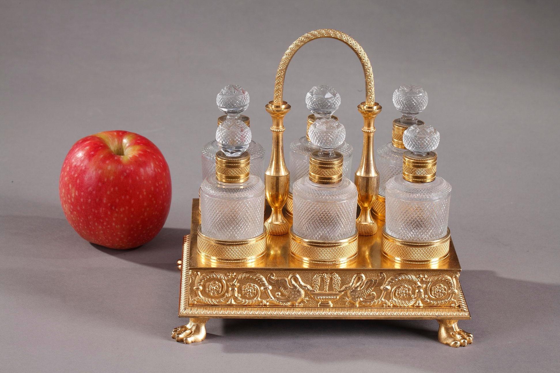 Beautiful perfume cellar with six cut-crystal bottles and their stoppers flawlessly cut in a diamond point motif. A rossette adorn the top of the stoppers. The rectangular gilt bronze platter is highlighted with flowery scrolls and some typical