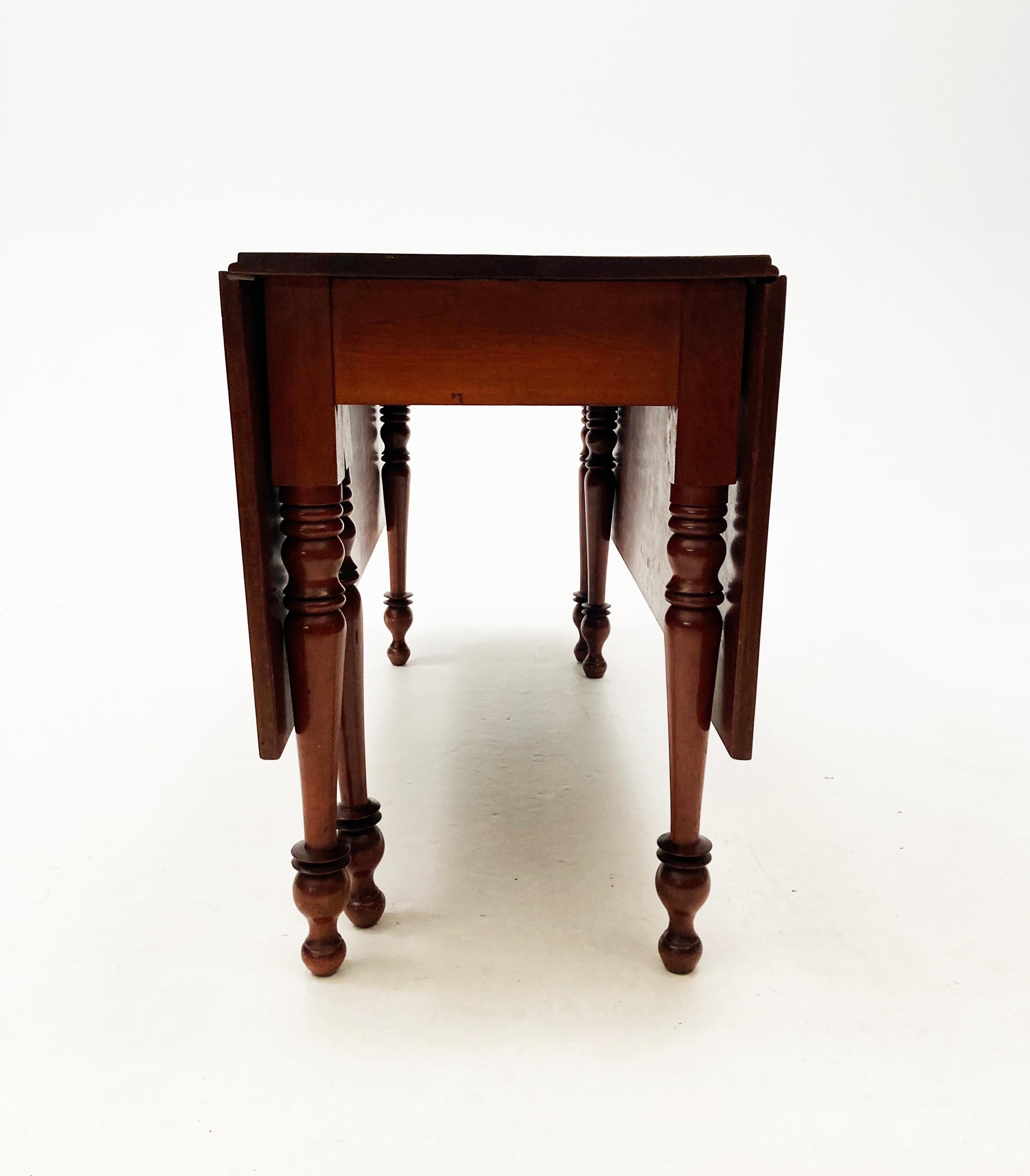 Not your ordinary drop-leaf table, this early 19th century cherry gate-leg, drop-leaf table was hand-planed and hand-turned to create a wonderful dining table that doubles as a console or hall table when the leaves are down. The turned legs are