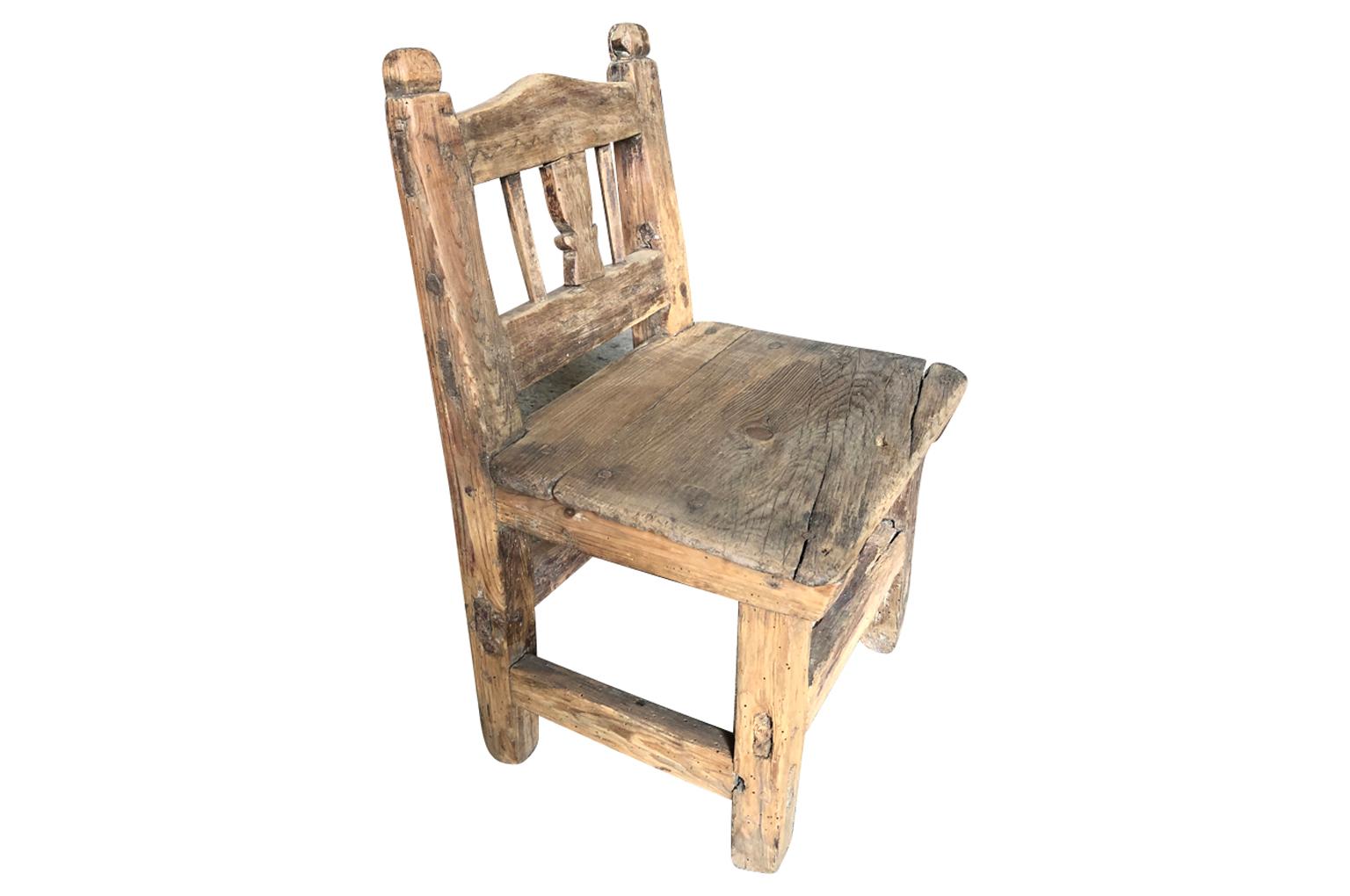 A very charming early 19th century Child's chair from Spain. Soundly constructed from Meleze wood - a very dense pine. A delightful Primitive piece with beautiful carving detail.