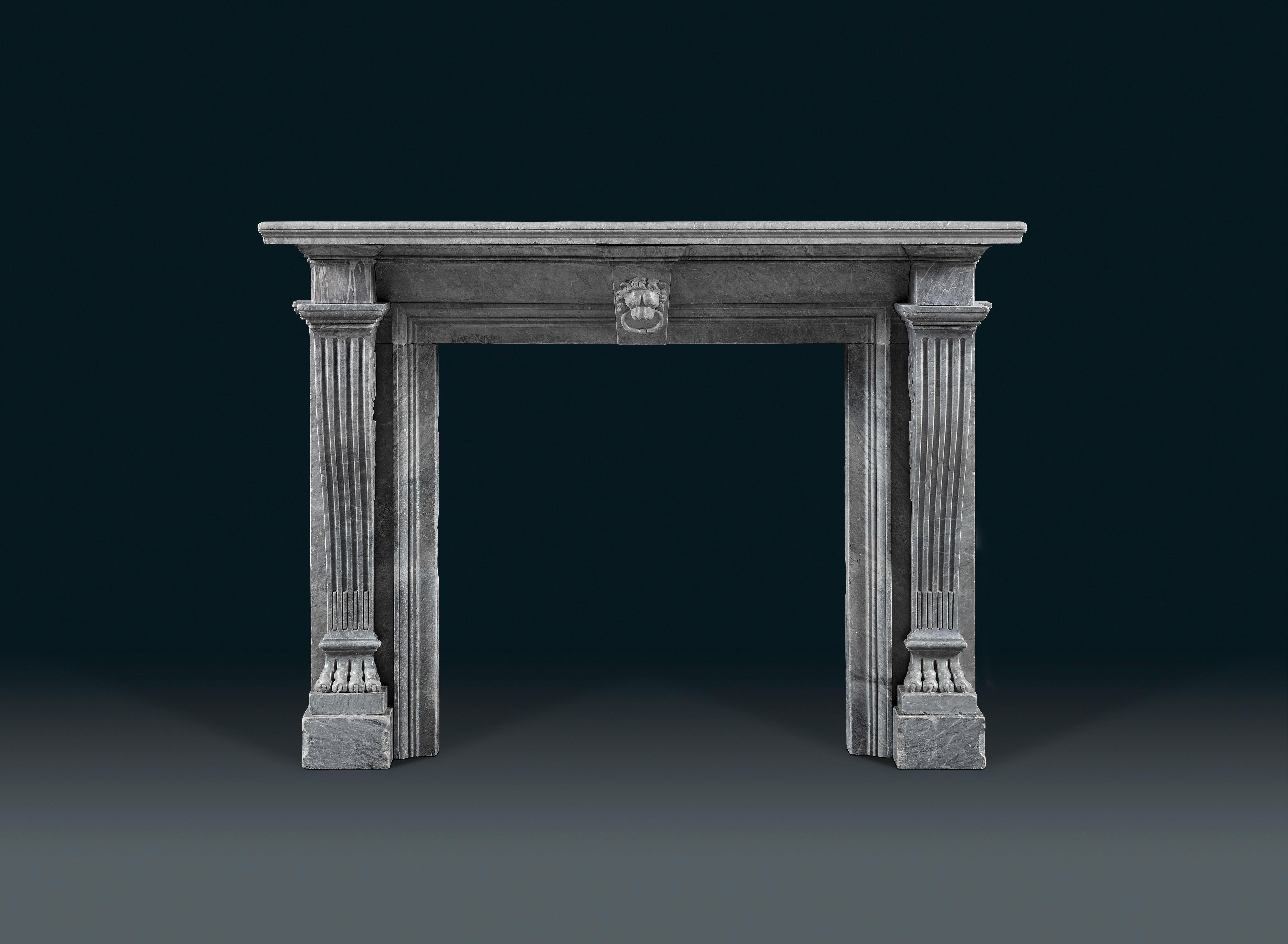 An early 19th century chimneypiece of Italian Bardiglio Imperiale marble with delicate swirls of grey and blue, probably sculpted in Italy for the English market; The rectangular shelf above the frieze which is centred with a key stone decorated