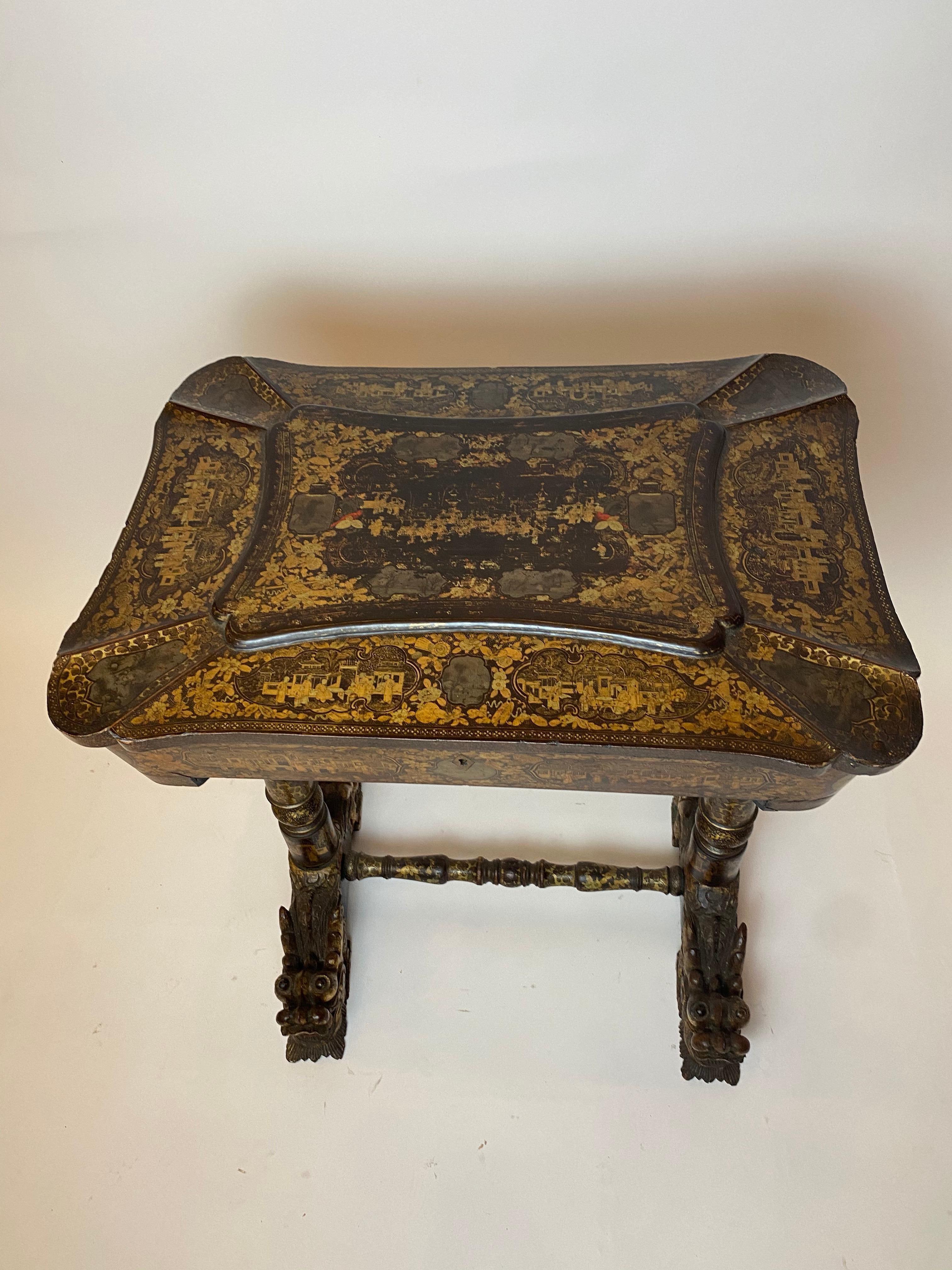 Early 19th century Chinese export lacquer and gilt work table from the Qing Dynasty, with carved gilt dragon head feet, with the table of canted rectangular form, with moulded top, the entire finely decorated with the typical figural landscape and