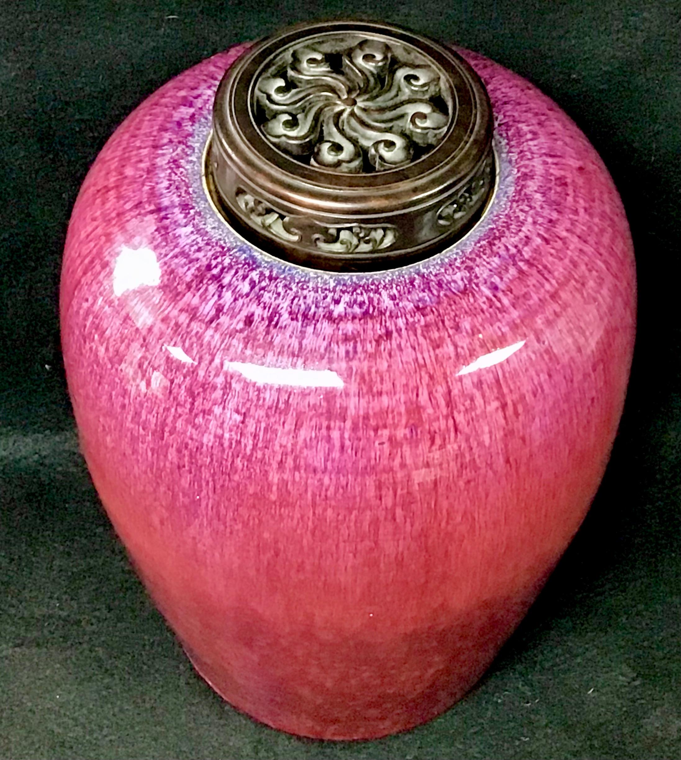 Chinese oval flambe ginger jar with carved wood lid. Flambé ware captivates with beautiful irregularity and vibrant blue and purple tones. These streaky, iridescent colors are the result of metallic materials in the glaze that cause separation at