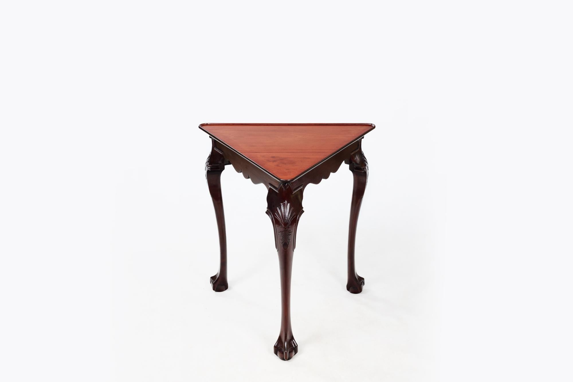 Early 19th Century unusual corner serving table with moulded triangular mahogany top over shaped frieze. The piece sits on three cabriole legs with carved shell motif to the knees and terminates on ball-and-claw Feet.