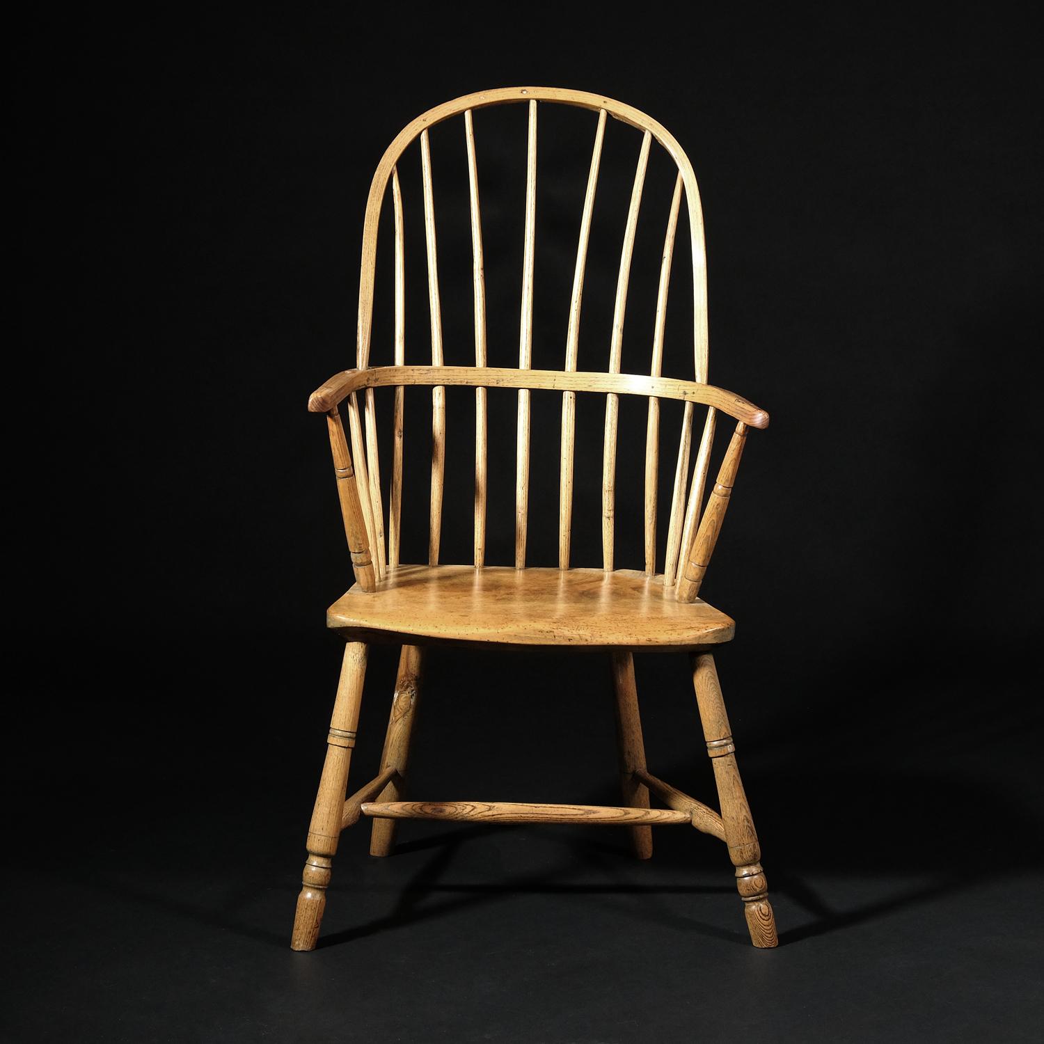A delightful stick back Windsor armchair in sycamore and ash. The solid slab seat with subtle saddle shaping supported by egg and reel turned front legs (one an old replacement perhaps) and plain slightly tapered rear legs. Two turned arm supports