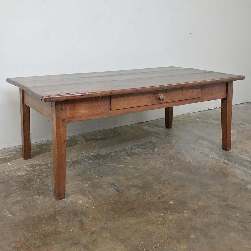 Early 19th century Country French fruitwood coffee table was hand-hewn from solid planks of old growth fruitwood to last for centuries, and includes a large mid-mounted drawer for your added convenience. The ever-pragmatic French would harvest