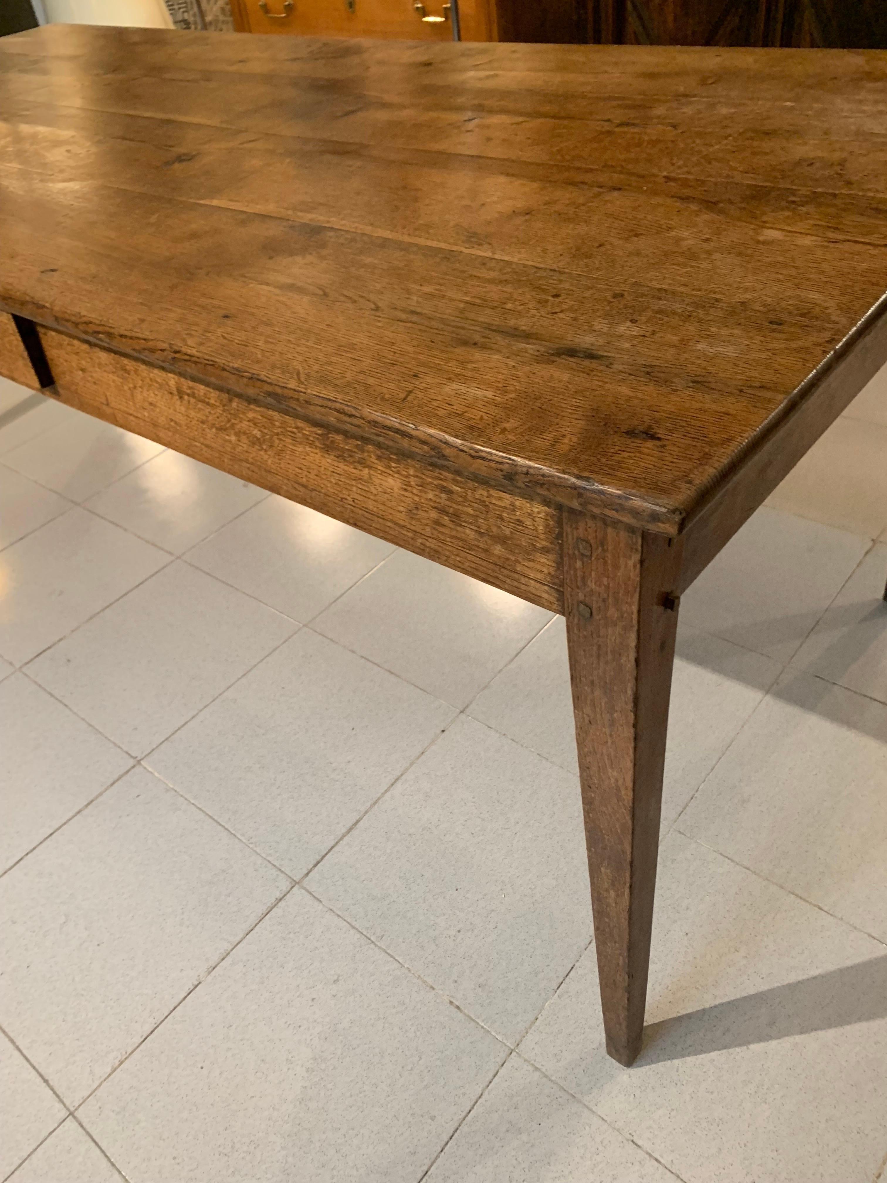 French farm table from the early 19th century, in oak wood, both the top and the legs, it is a very simple and elegant table with a small skirt and some conical legs, with a single drawer in the middle of the table, made with pegs, retains all its