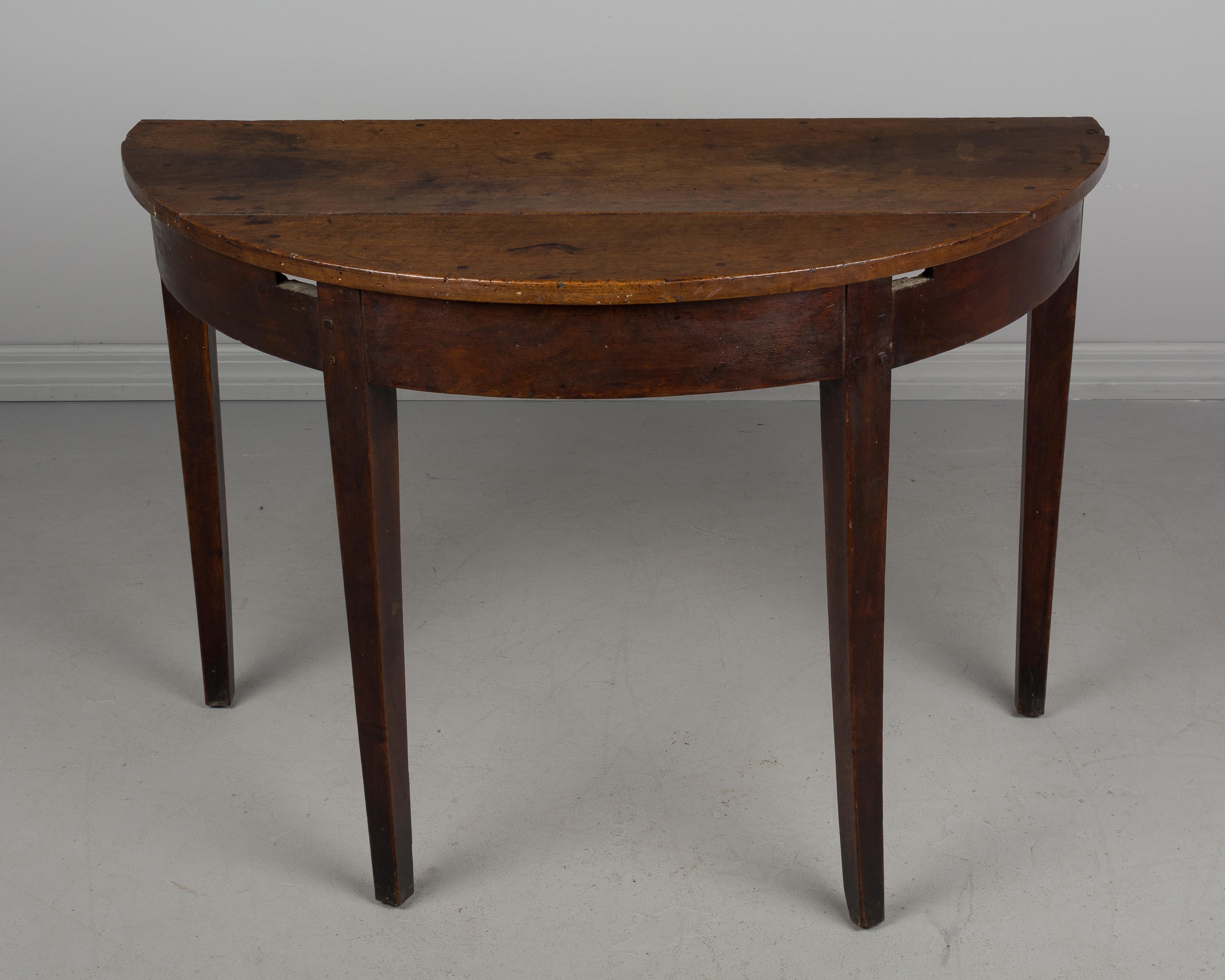An early 19th century Country French demilune console table made of walnut. Small hidden dovetailed drawer in the back. Pegged construction. Waxed patina. This table used to have a top and a fifth leg.