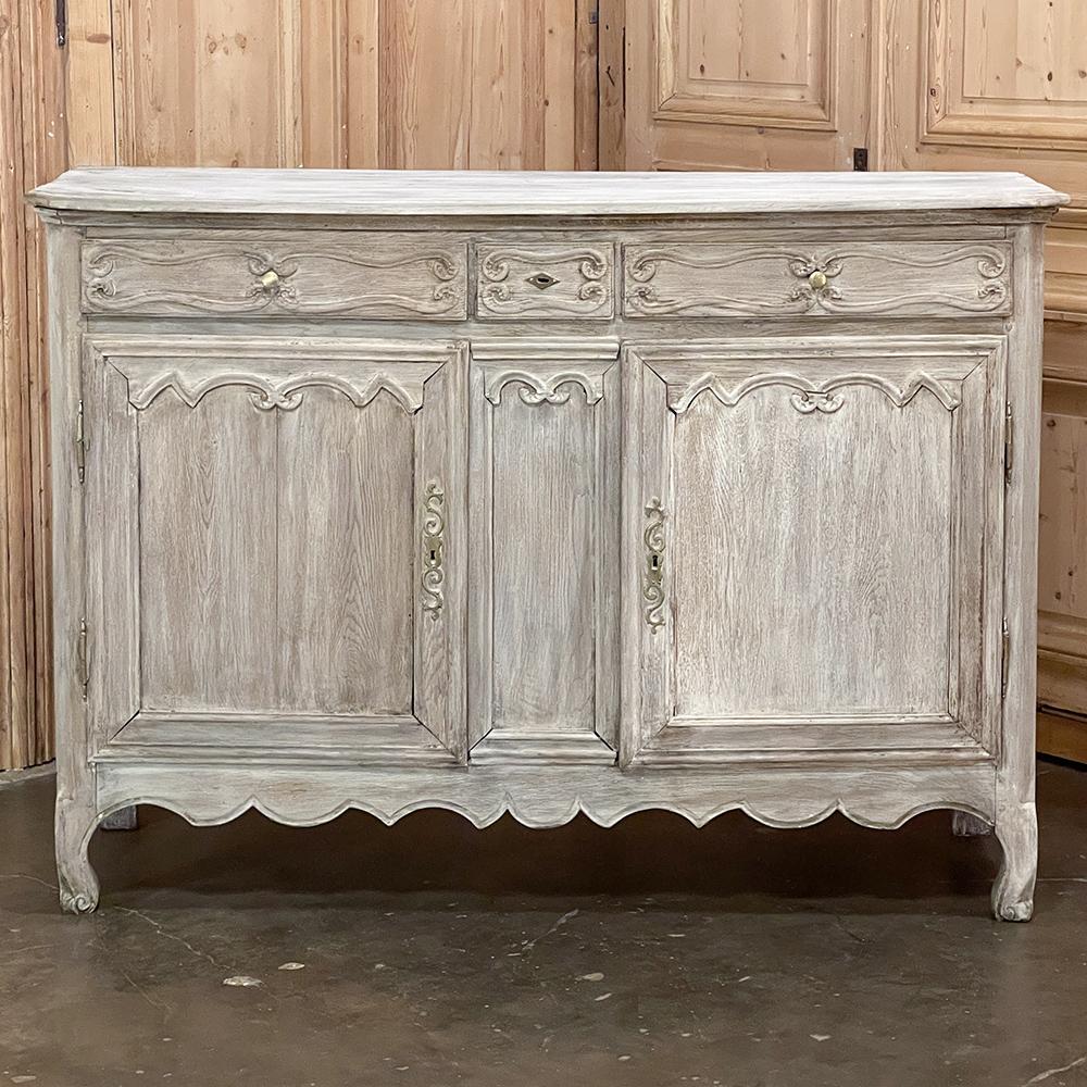 Early 19th century Country French whitewashed buffet is an example of the restrained expression of the style, with tailored scrollwork defining the molded detail across the drawer tier and the tops of the cabinet directly underneath. An undulating