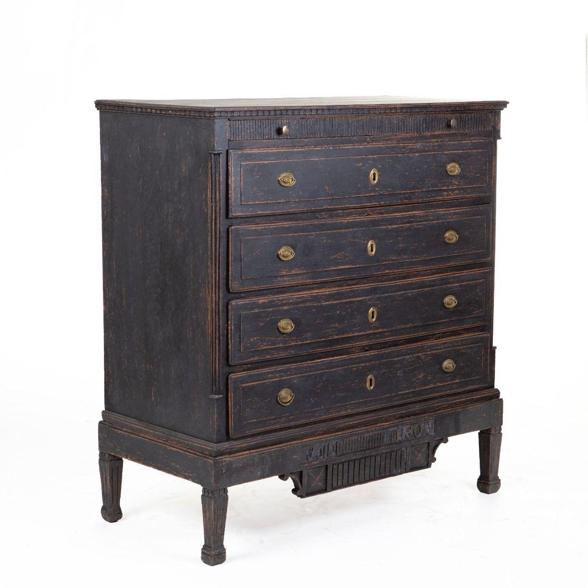 Danish Gustavian chest of drawers from 1803, crafted in black-painted wood with original brass fittings and locks.
Profiled top above a carved dentil frieze.
The front has five drawers: a narrow top drawer with reeded front, above four larger