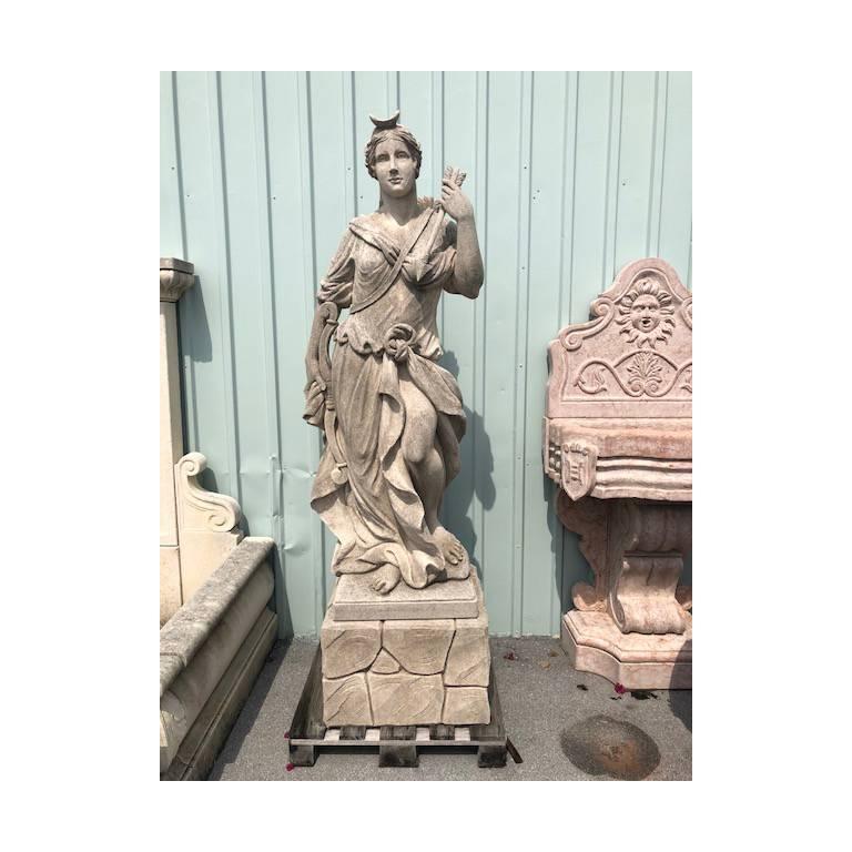 Early 20th century, a detailed hand carved statue of Diana in limestone, with minor damages and aged surface. In Roman mythology she was the heavenly goddess of hunt, the moon and the birthing. Associated with the animals and the woodland, she had