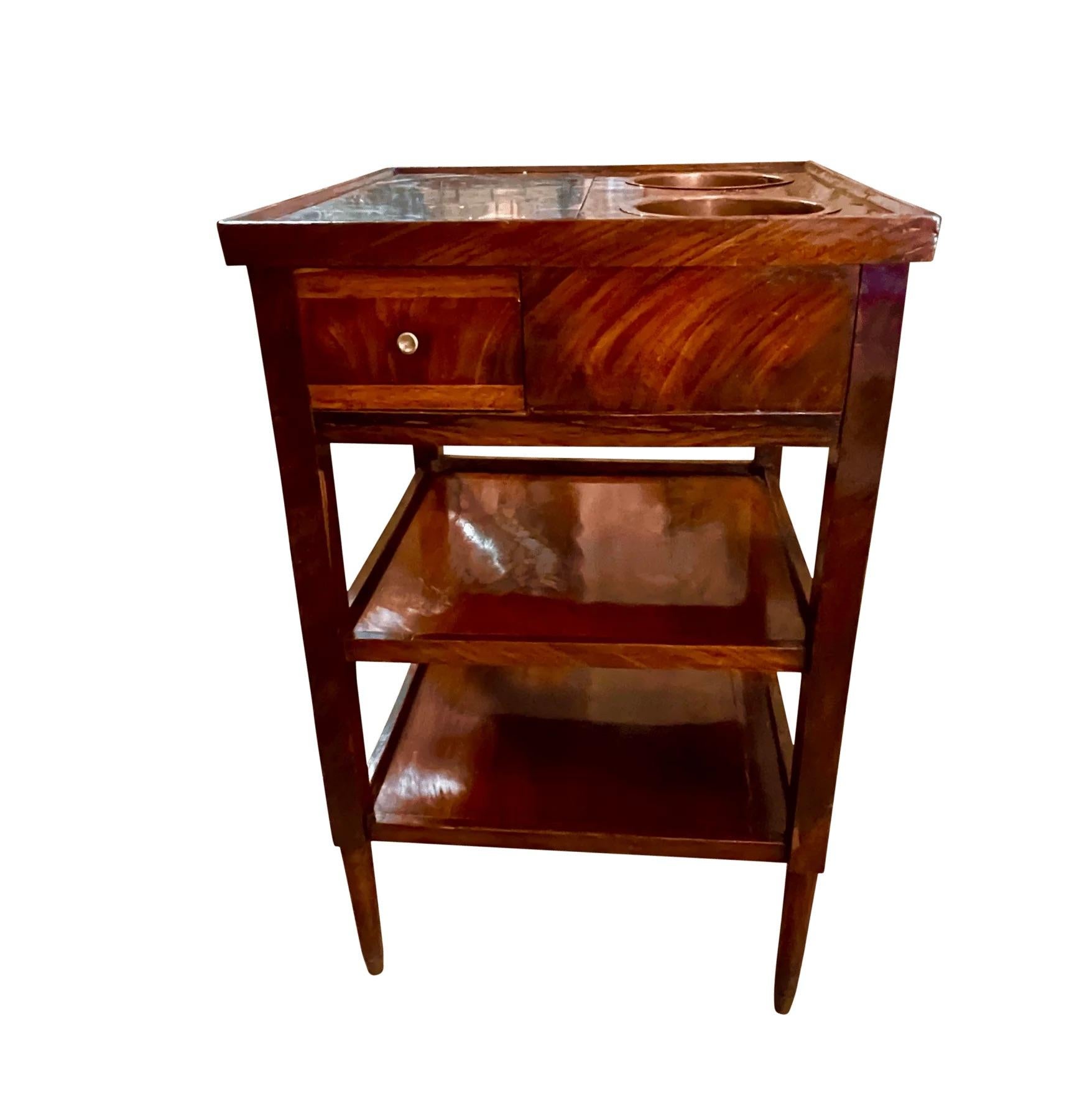 A Directoire mahogany three-tier rafraichissoir or wine serving stand, early 19th century having a marble top, and copper liners. 

