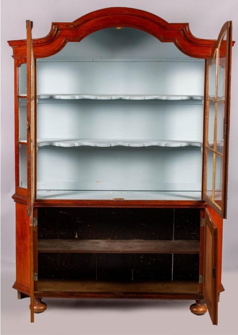 Early 19th century Dutch baroque style cherry cabinet with glass doors. Arched rectangular cornice fitted with two glazed mullioned doors over a lower case fitted with two doors on bun feet. Lovely piece that will have a presence in any room.