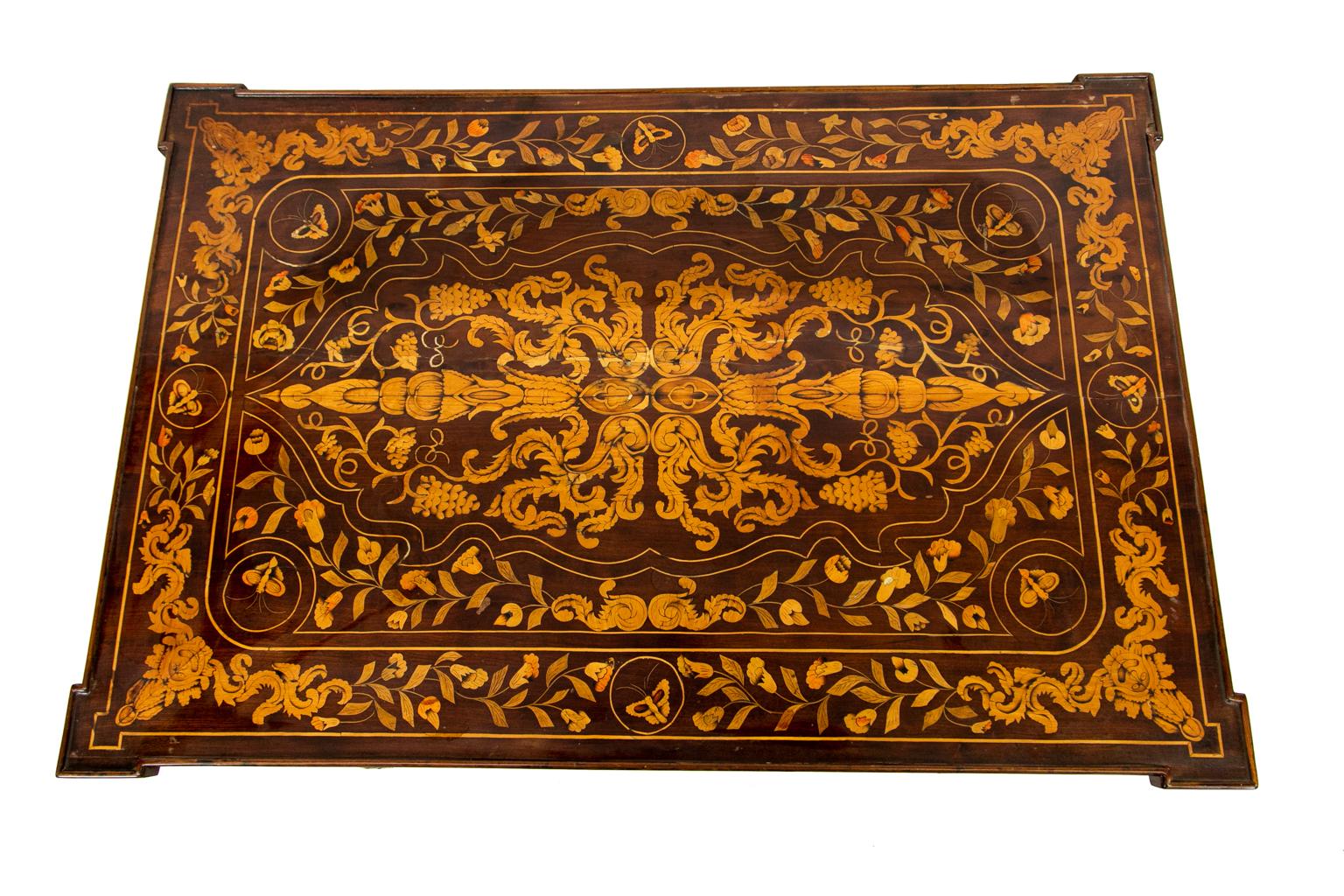 Early 19th Century Dutch Marquetry Center Table, the top inlaid with flowers, leaves, and butterflies with book matched masks on the corners. It is fully inlaid on all four sides. The inlaid tapered legs terminate in brass castors.
        