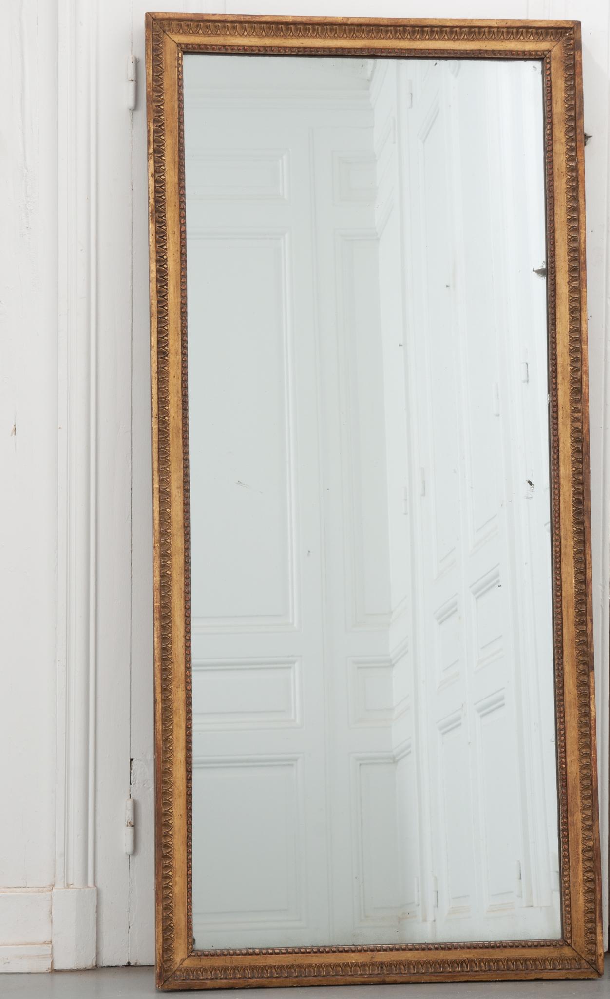A perfectly sophisticated Dutch Regency giltwood mirror, circa 1810. Perimeters of lamb's tongue and bead outline the original mirror. The symmetrical giltwood frame has worn slightly with time and use, giving it a wonderful patina. Some signs of