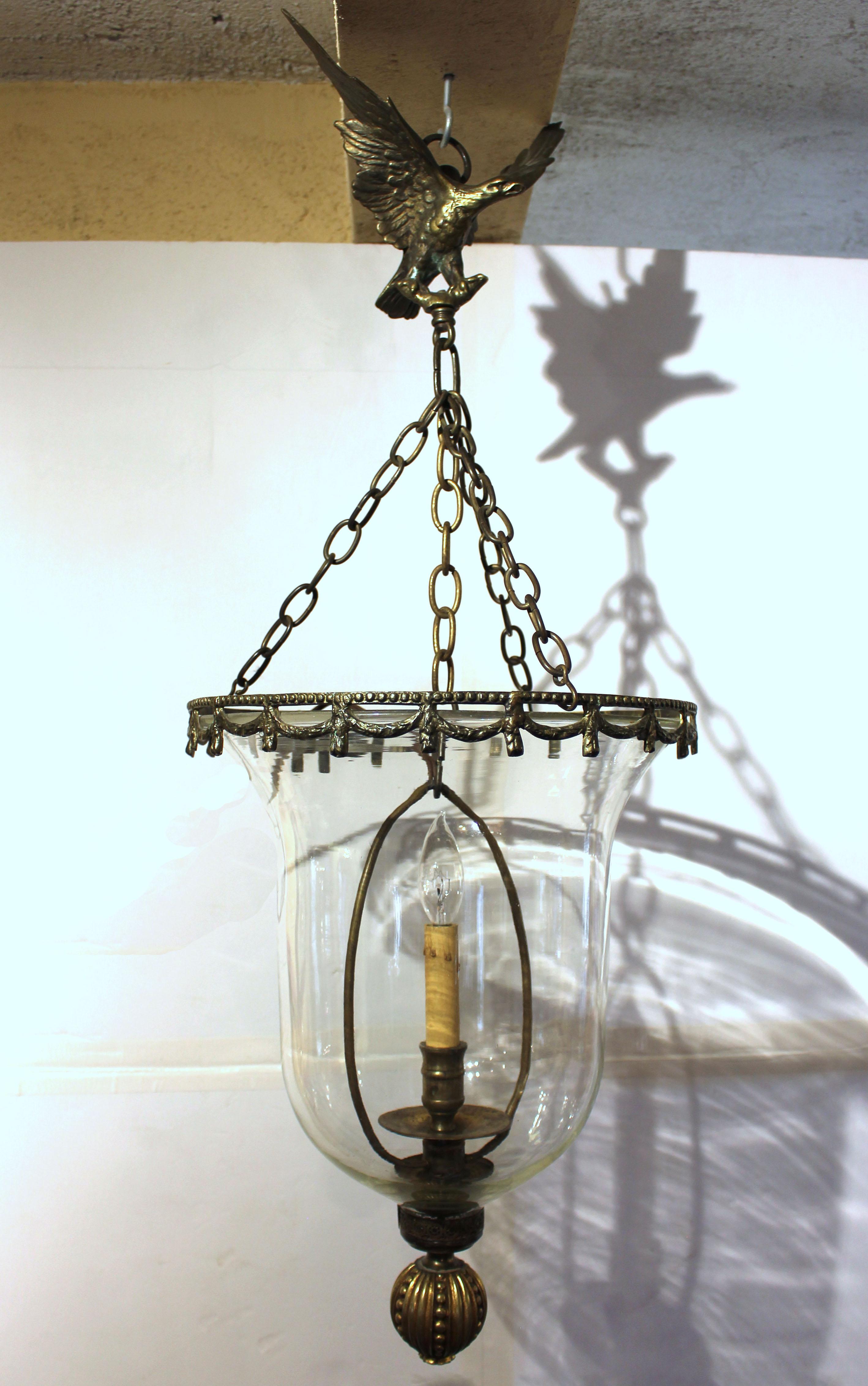 Early 19th century eagle mounted hall lantern, Anglo-American. Cast & gilt brass with blown glass tapering to pierced collar to draw air. Current electrical system replaces a single candle. Currently designed for a ceiling canopy or hook. 
13.75