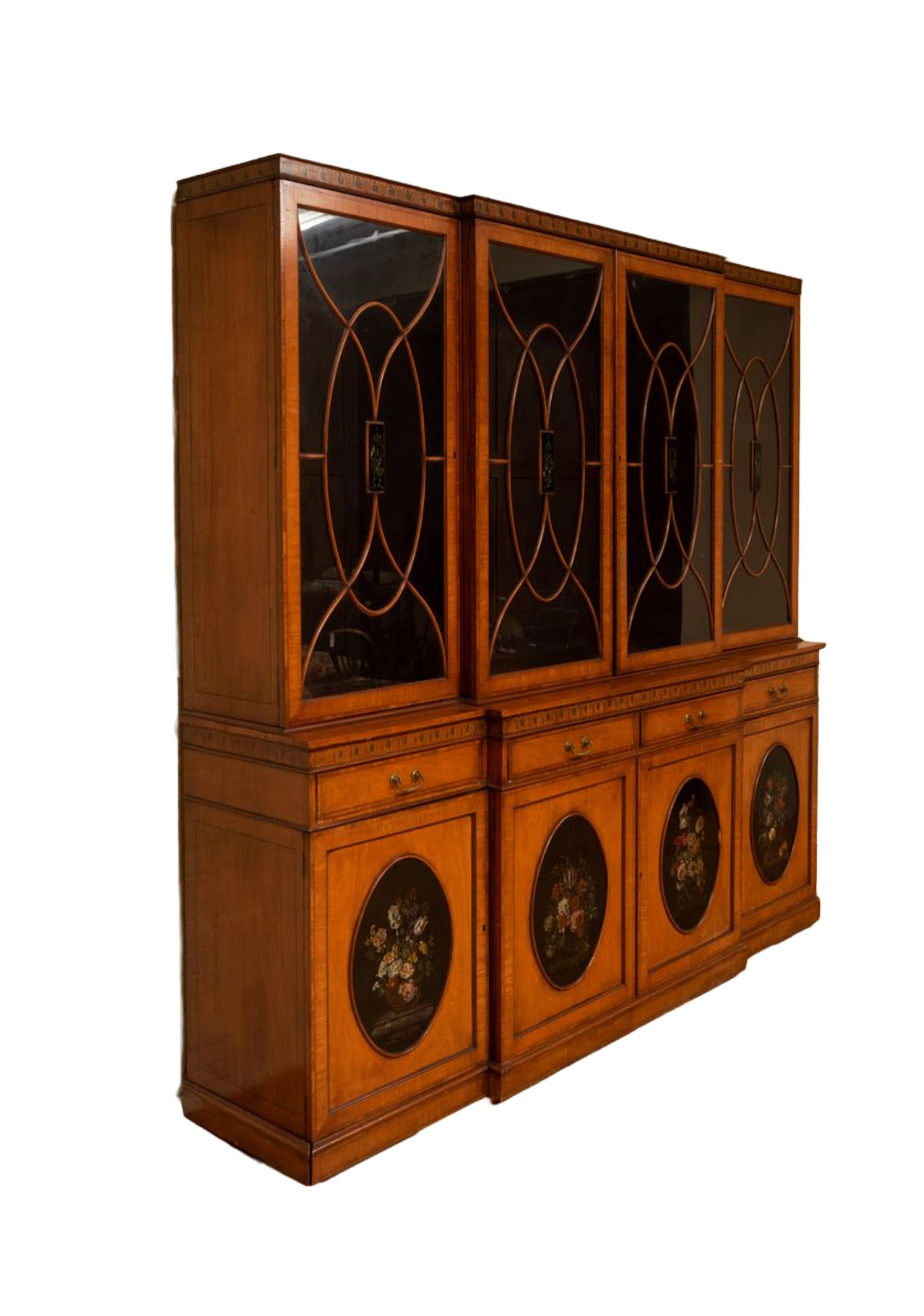 Beautiful craftsmanship mahogany bookcase / china cabinet in the Edwardian style with a flat top molded cornice above four cross-banded glazed doors. Each features a centered hand painted musical trophy panel design details. The outset of the lower