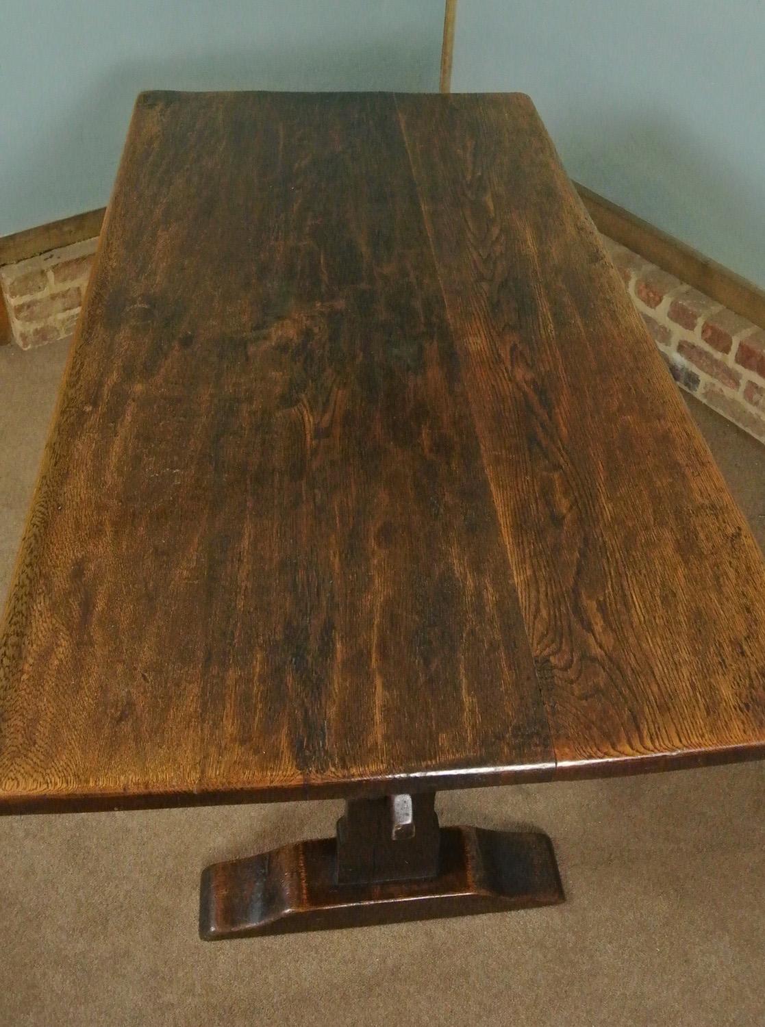 A very substantial and beautiful solid elm refectory table with twin boarded top over large supports with sleigh feet and united with a single original and removable elm stretcher which is fixed with large wedged pegs at either end.

The whole is