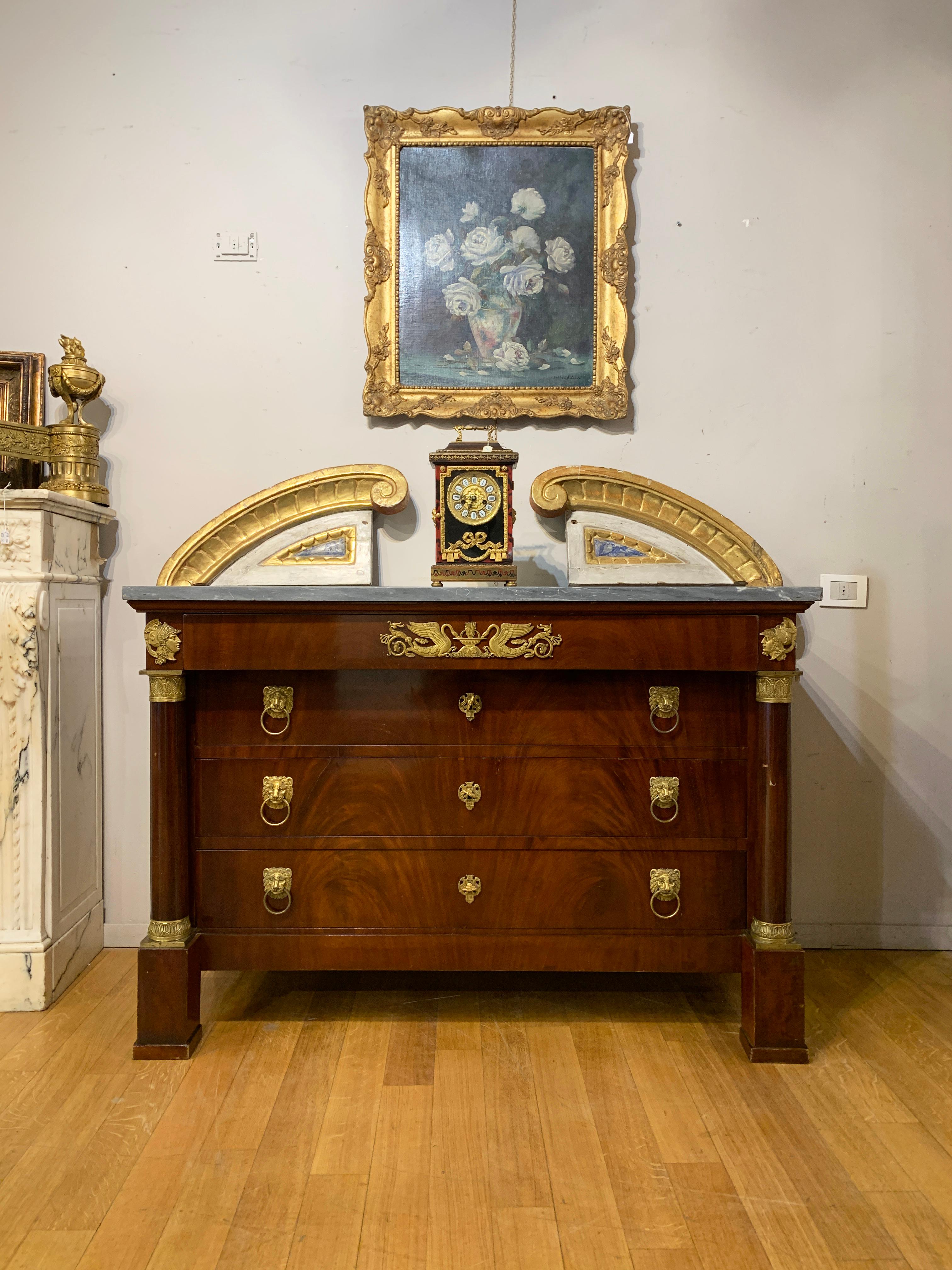 Elegant chest of drawers from the Empire period in mahogany feather with lost wax cast and gilded bronze friezes. The chest of drawers has three large drawers and a smaller one below the top. The corners of the chest of drawers are also
