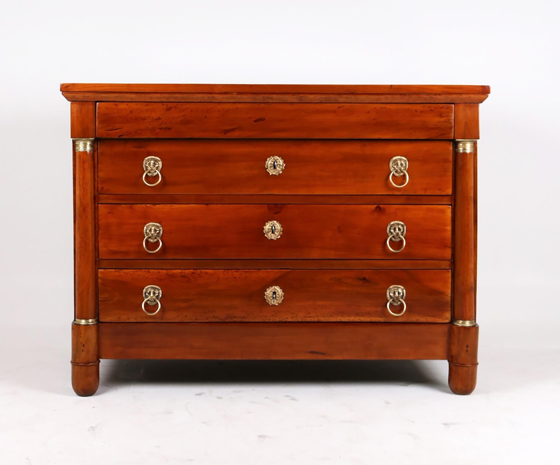 Four-bay chest of drawers from the French Empire around 1820.
Solid cherry wood piece of furniture standing on round feet in the front and cleated feet in the back.

The three lower drawers are equipped with ornate brass fittings in the form of