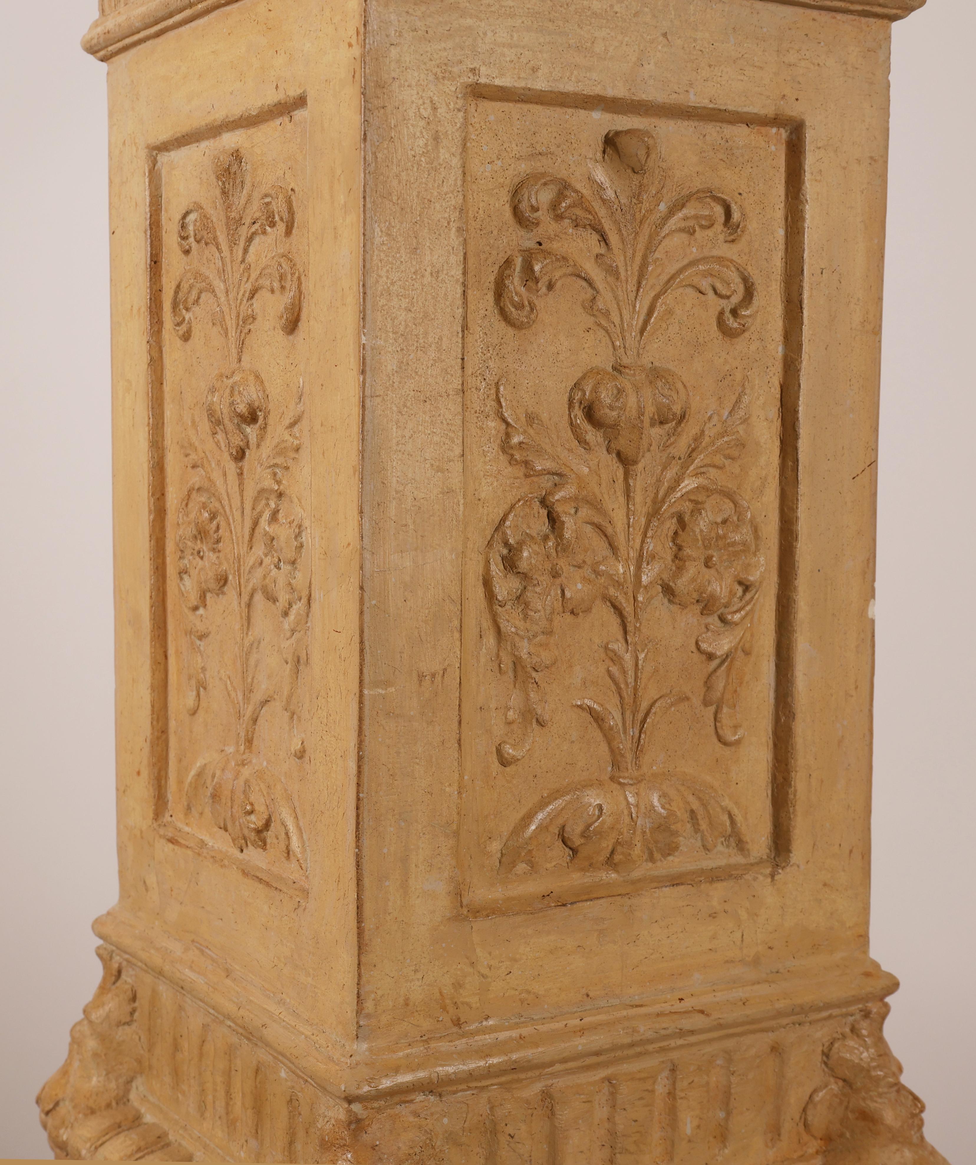 A decorative Empire column made of plaster. It was likely produced in Sweden during the early 19th century. The color is the original, restored finish. The column features decorations of maskarons and acanthus leaves.