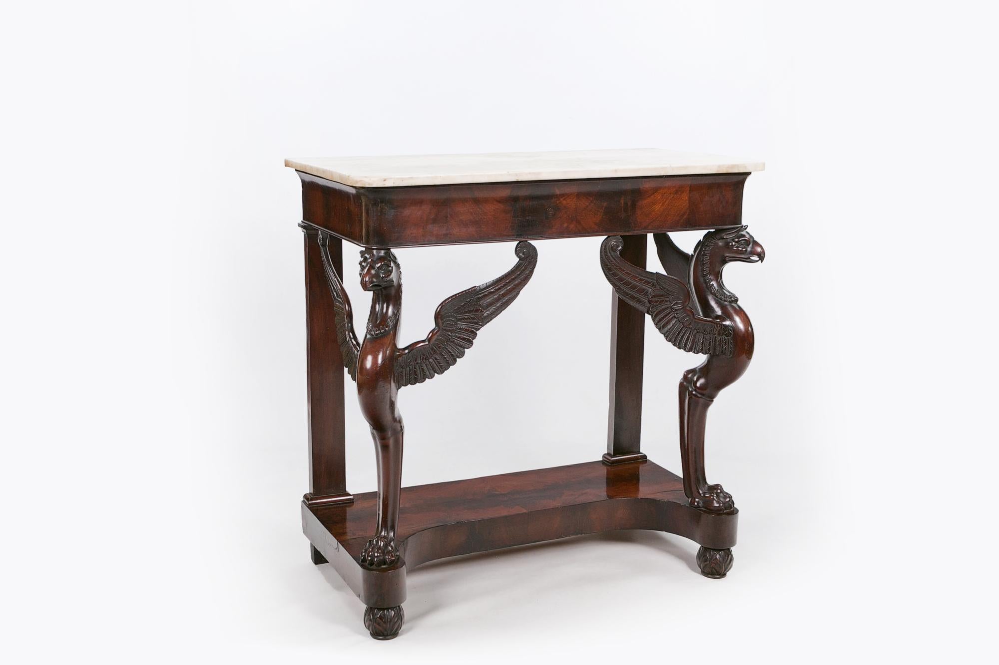 Early 19th century Empire flame mahogany and marble console table, the statuary white marble top of rectangular form raised over plain frieze supported on two ornately carved winged griffin legs to the front and two straight to the rear raised over