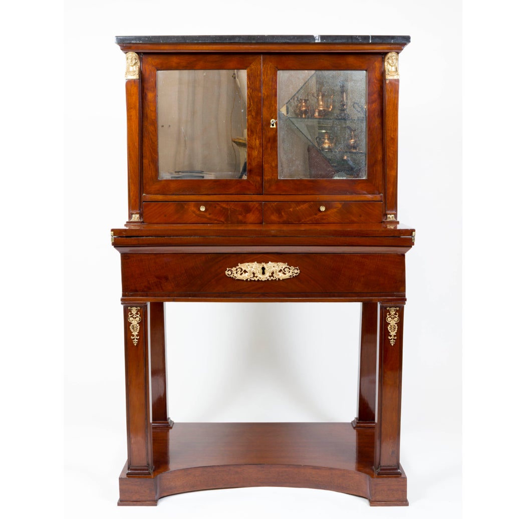 An early 19th century gilt bronze and walnut veneer ladies desk or dressing table or vanity, with a rectangular grey fossil marble top above two mirror paneled doors and two drawers, flanked by Greek Revival female caryatids, above a folded leather