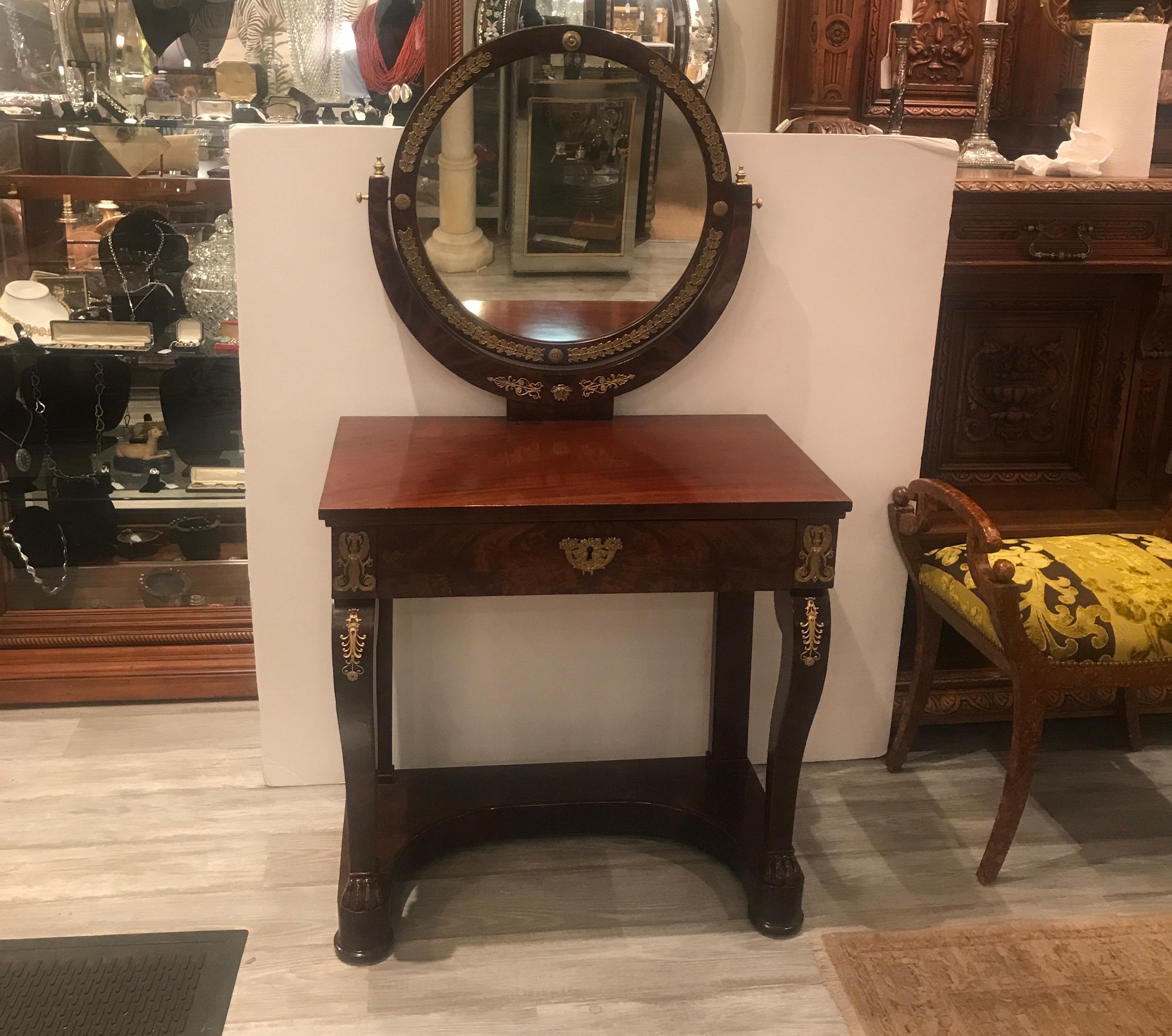 Elegant and formal French Empire mahogany vanity with ormolu mounts. The circular mirror over a rectangular top with lower drawer and gilt bronze mounts all-over. The piece has been recently French polished with a well cared but age appropriate