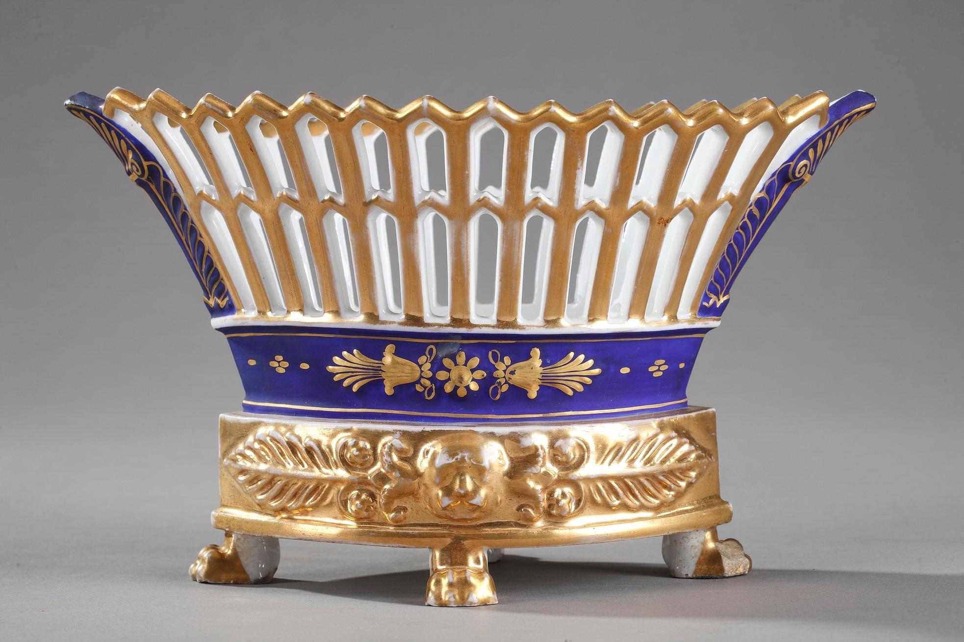 Small French basket in white and blue porcelain, highlighted with delicate gilt-accented floral motif. Crafted in the early 19th century, this service dish features a radiating latticework flanked by gold colored palmette. It is set upon an oval
