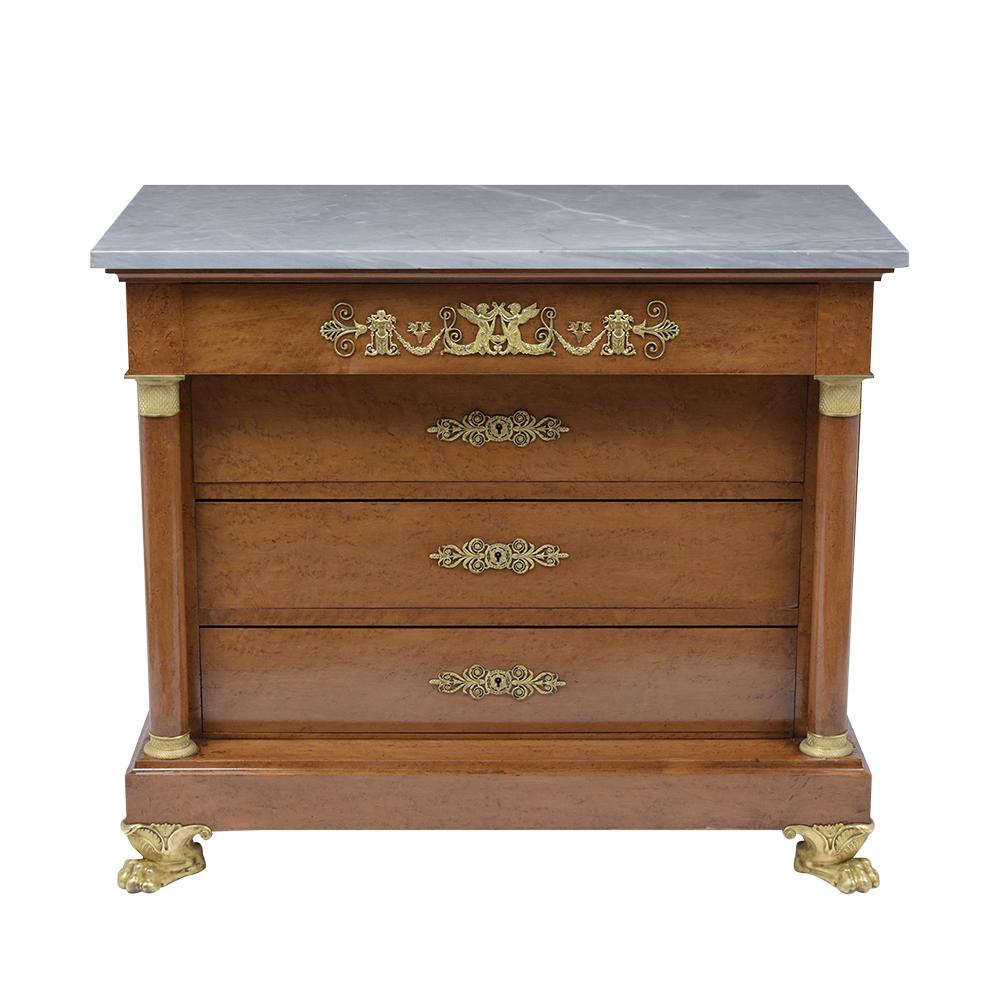 This Early 19th century Empire Commode is in great condition, is made out of solid wood covered in birch veneers with a walnut color and a rich patina finish. This Chest if Drawers features its original grey color marble-top, two carved columns each