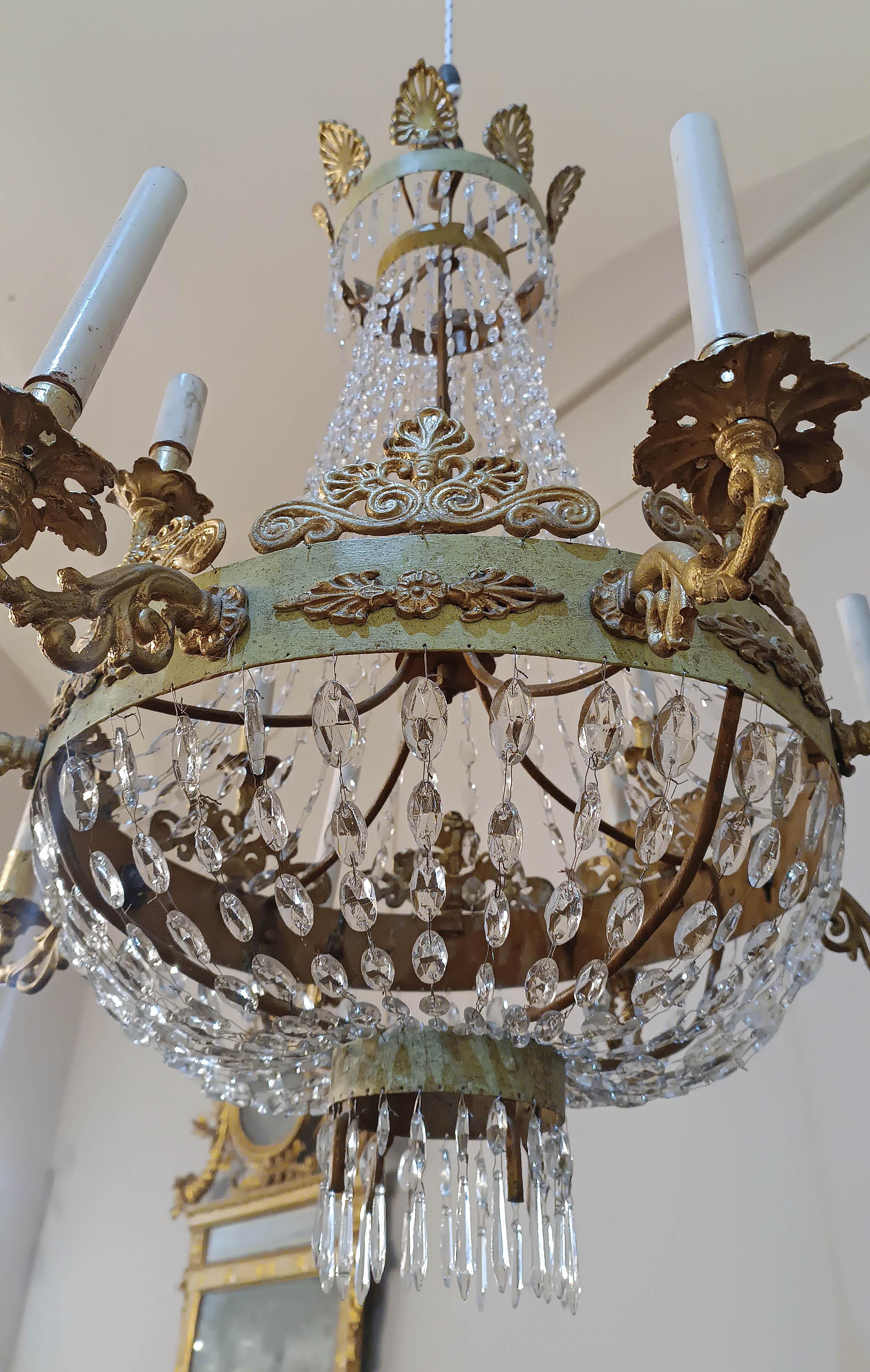 Beautiful and elegant tundish chandelier with twelve lights. Made of wrought iron with lead bobèches and cast metal candle holders, this chandelier features bands painted in a delicate sage green, enriched with gold-painted palmette decorations. The
