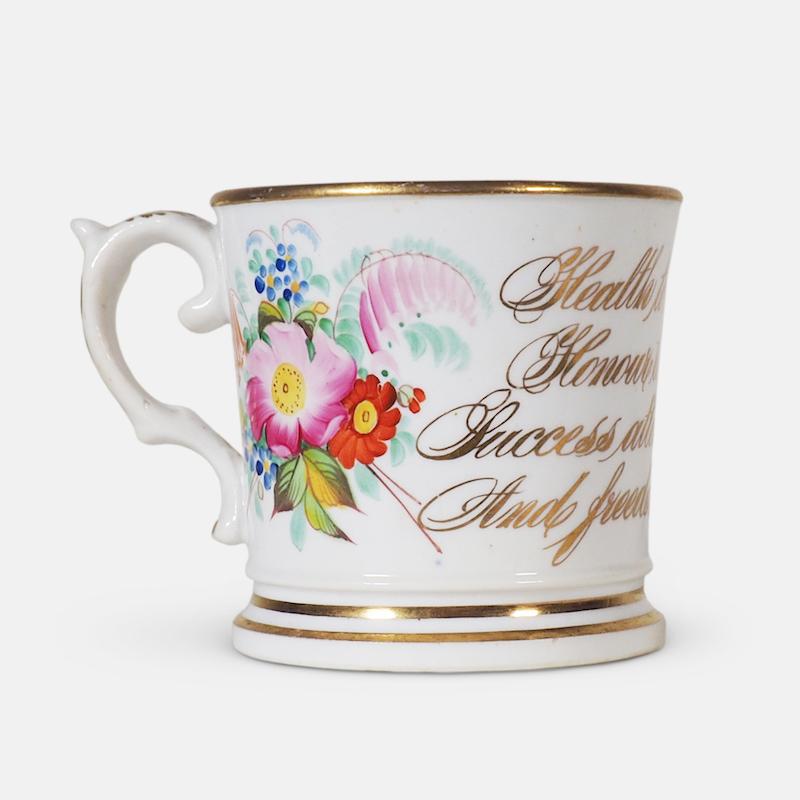 An important early 19th century English ceramic anti-slavery cup. Slightly tapered form, with bright gilt borders and hand painted with floral sprigs flanking abolitionist script: 'Health to the sick, honour to the brave, success attend, true love