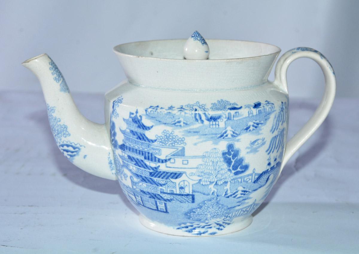 The early 19th century child's teapot is decorated in the Blue Willow pattern, the most famous of all English Staffordshire pottery designs. Illustrated and repeated on both sides are the Chinese couple on the bridge, the willow tree above them and