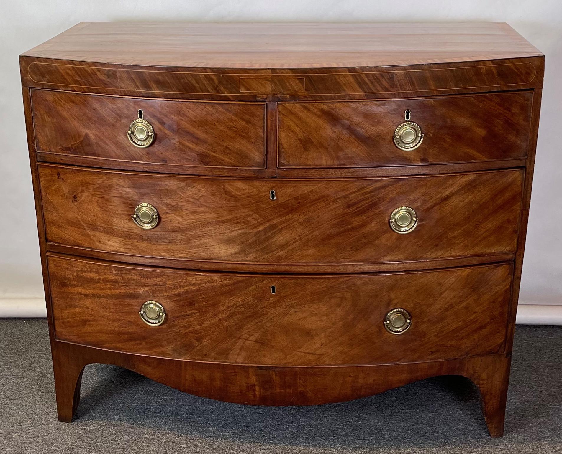 A small and elegant early 19th century George III bow front chest in faded mahogany and boxwood stringing with two small drawers over two graduated long drawers on splayed French feet.