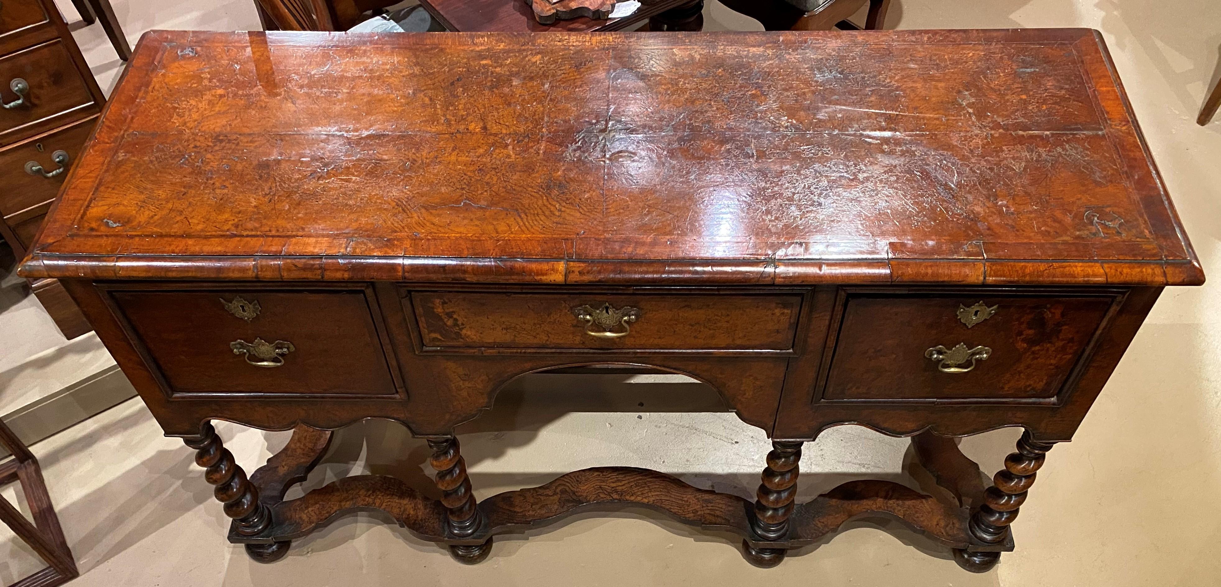 A finely carved burled walnut sideboard or server with rectangular top featuring cross-banded veneer molded edge border surmounting a center frieze drawer flanked by two fitted deep drawers, each featuring decorative brasses, all supported by six