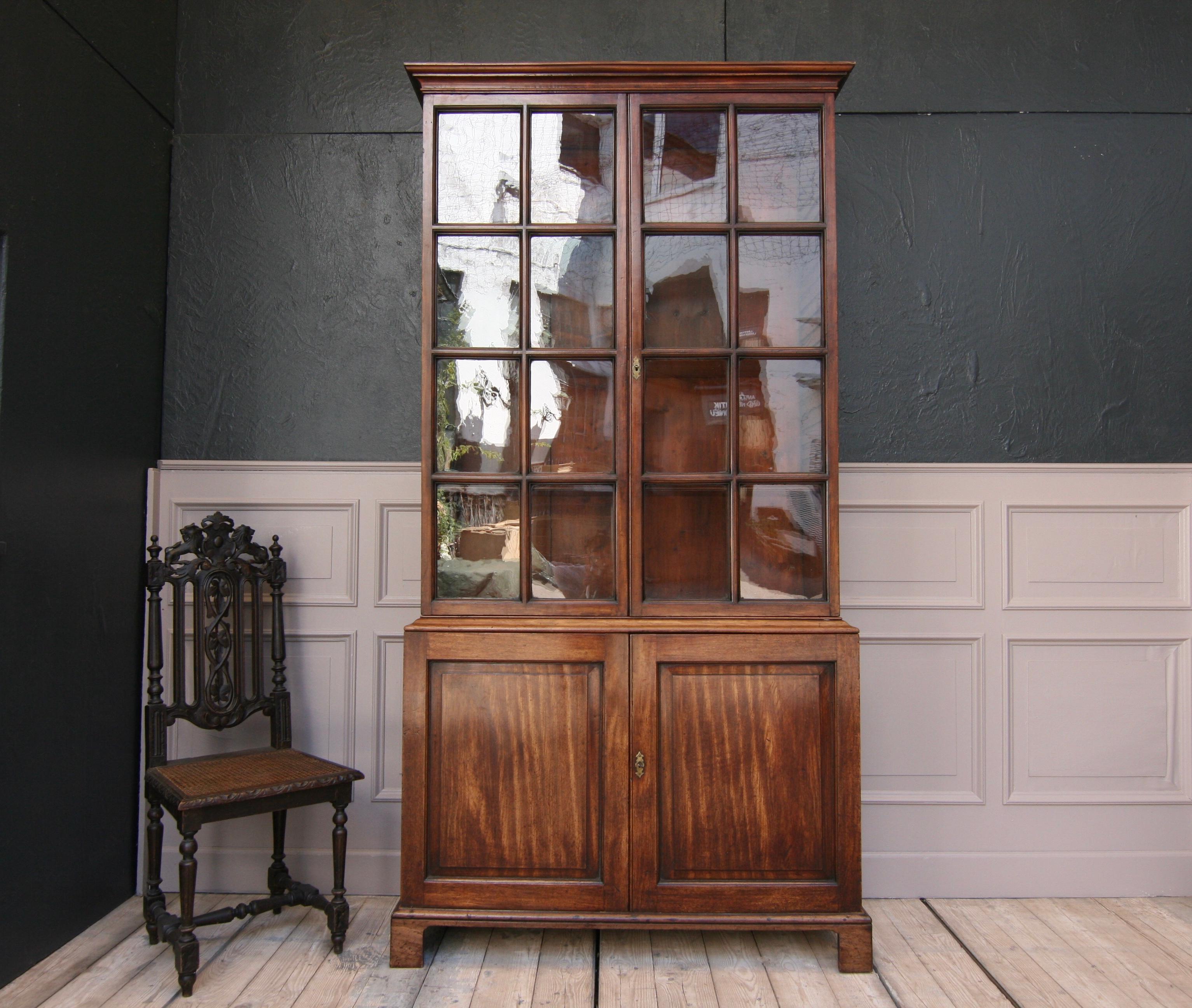 English mahogany bookcase or china cabinet, circa from the early 19th century.

Consisting of a base cabinet with 2 doors and a tall display case, also with 2 doors (with the original mouth blown glass), with 3 adjustable