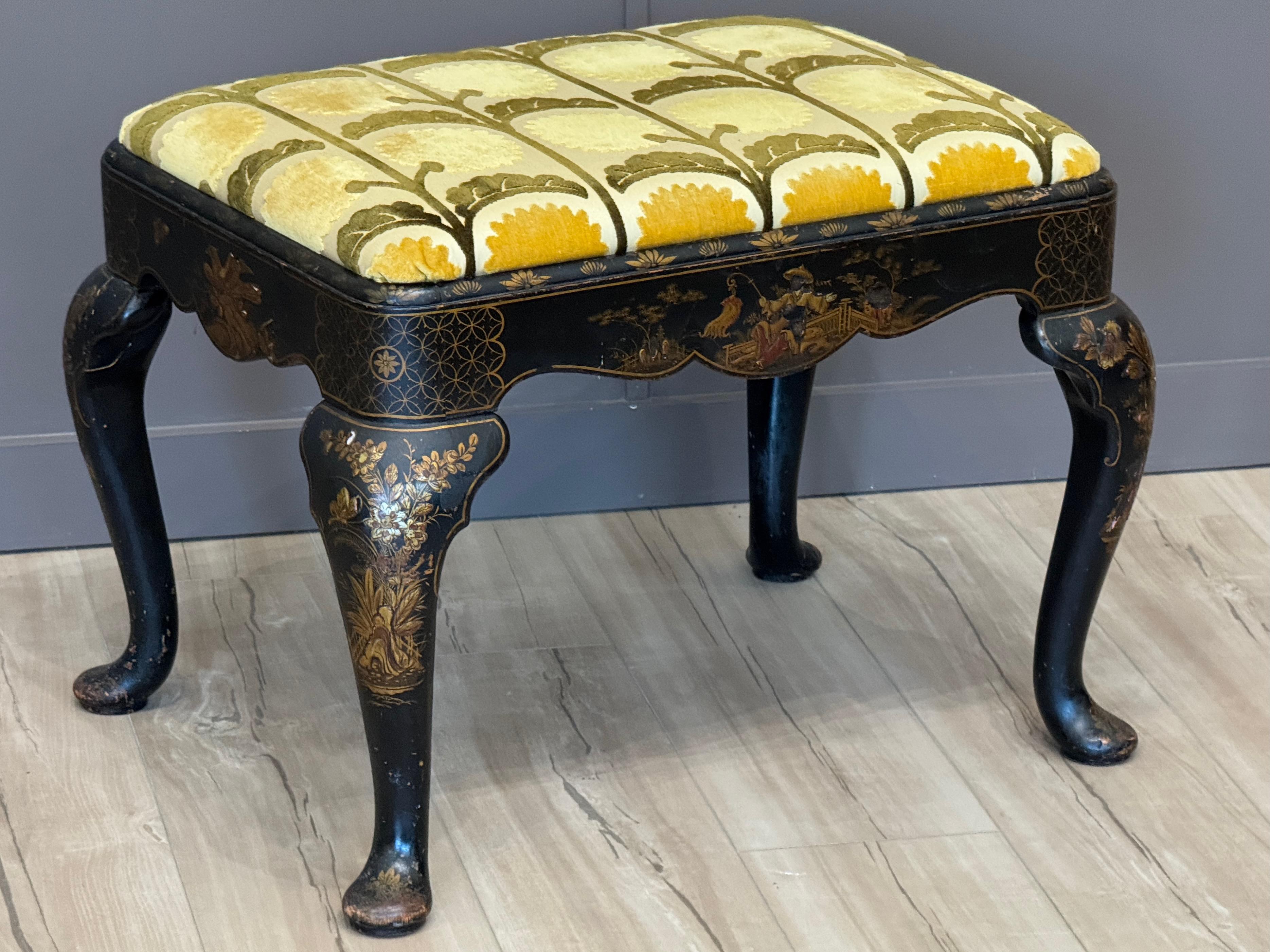 Reposapiés inglés de principios del siglo XIX decorado al estilo chinoiserie con detalladas figuras doradas y policromadas, aerosoles florales y motivos geométricos sobre un fondo de laca negra. Levantada sobre patas cabriolé Queen Anne y tapizada