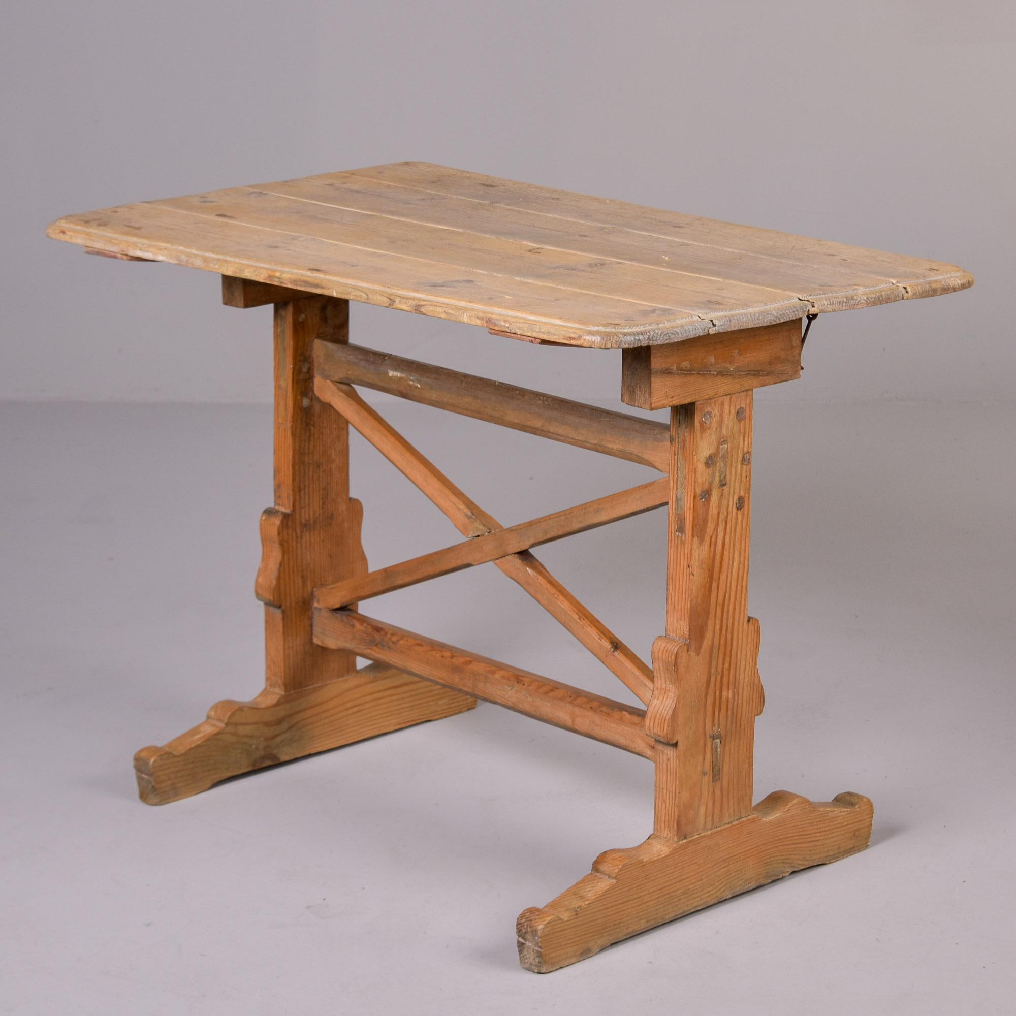 Encontrada en Inglaterra, esta mesa plegable de taberna data aproximadamente de 1820. La mesa parece ser de pino, con bastidor en forma de X y base de caballete. El tablero de la mesa se pliega hacia un lado para poder guardarla fácilmente.
