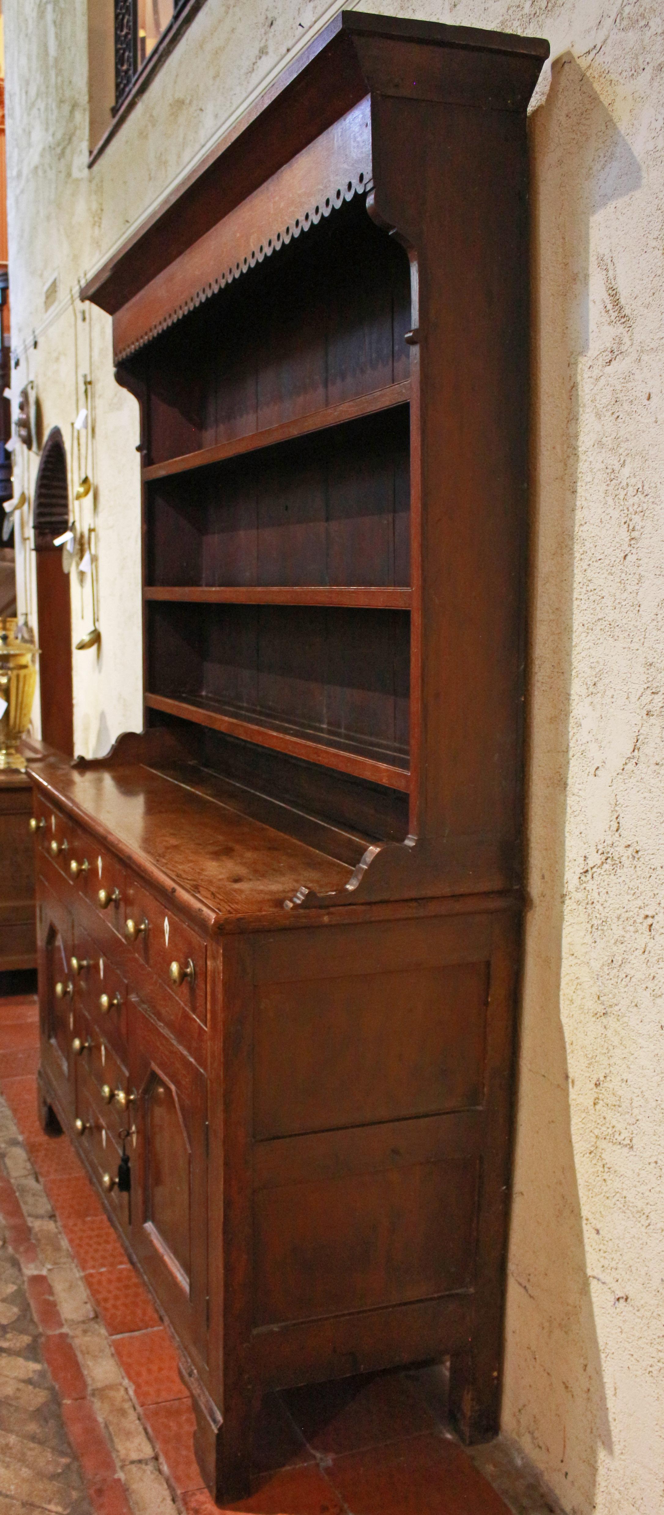 Comò inglese del primo Ottocento di epoca georgiana. Meravigliosa quercia pastosa. Modanatura a corona in grassetto con intaglio a cerchi concentrici e staffe sagomate nella parte superiore e alla base, 3 ripiani. 3 cassetti corti orizzontali su 3