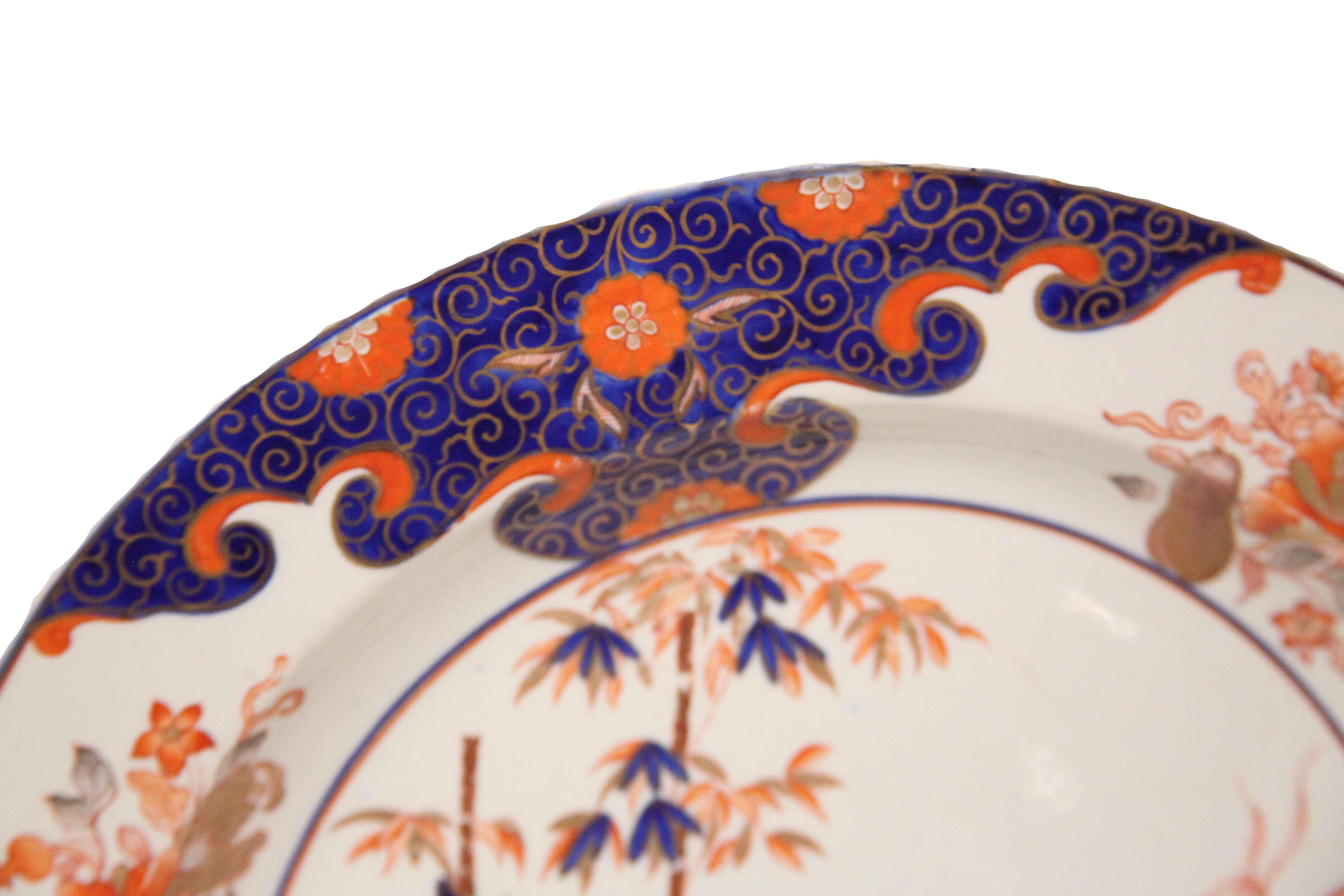 Early 19th century English ironstone charger, the border with a multitude of flowers and foliate on alternating cobalt and ivory backgrounds, the center featuring bamboo, floral and foliate motifs. Photos note minor gilding loss to center flower and