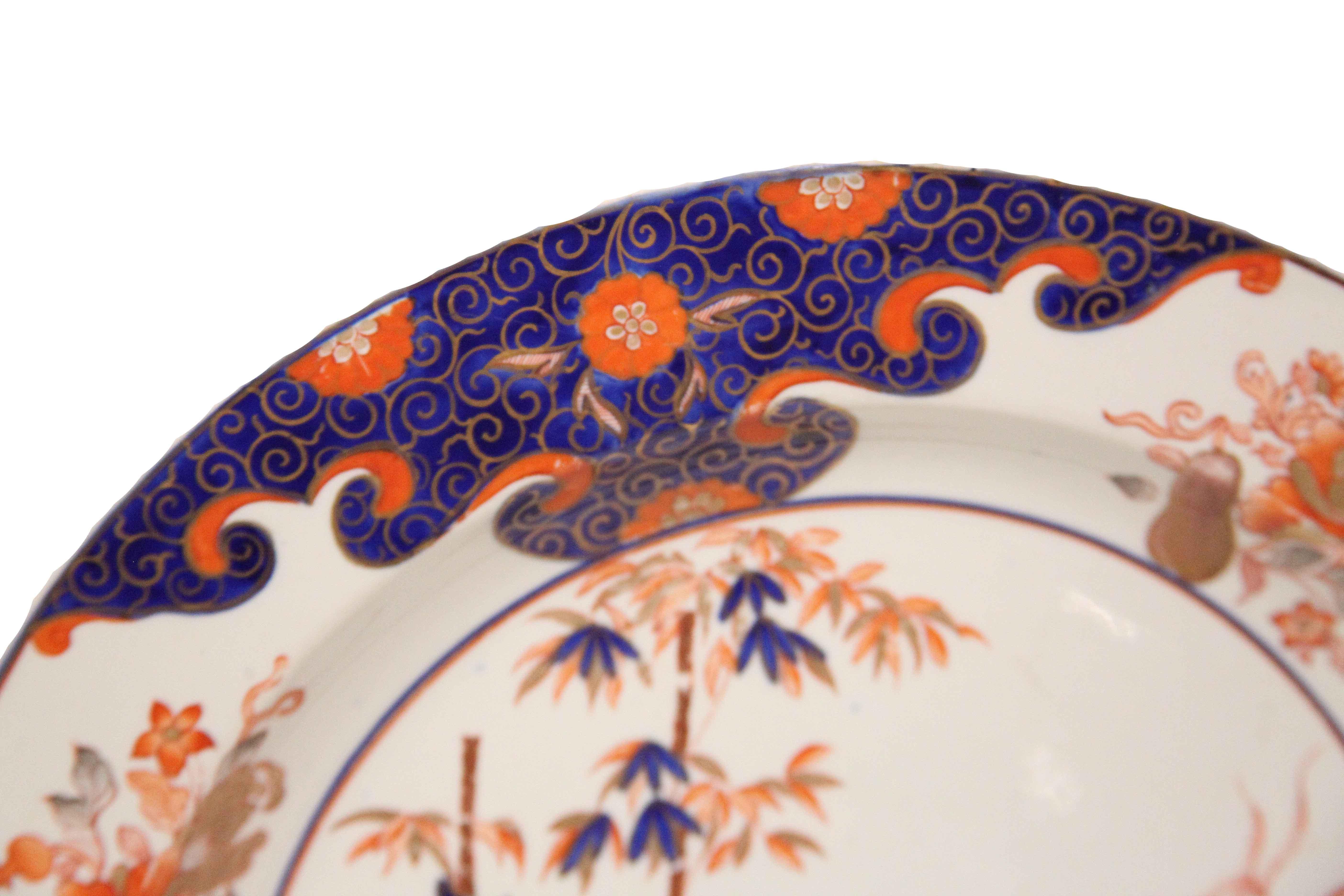 Cargador inglés de ironstone de principios del siglo XIX, el borde con multitud de flores y foliadas sobre fondos alternados de cobalto y marfil, el centro con motivos de bambú, florales y foliadas. Las fotos muestran pequeñas pérdidas de dorado en