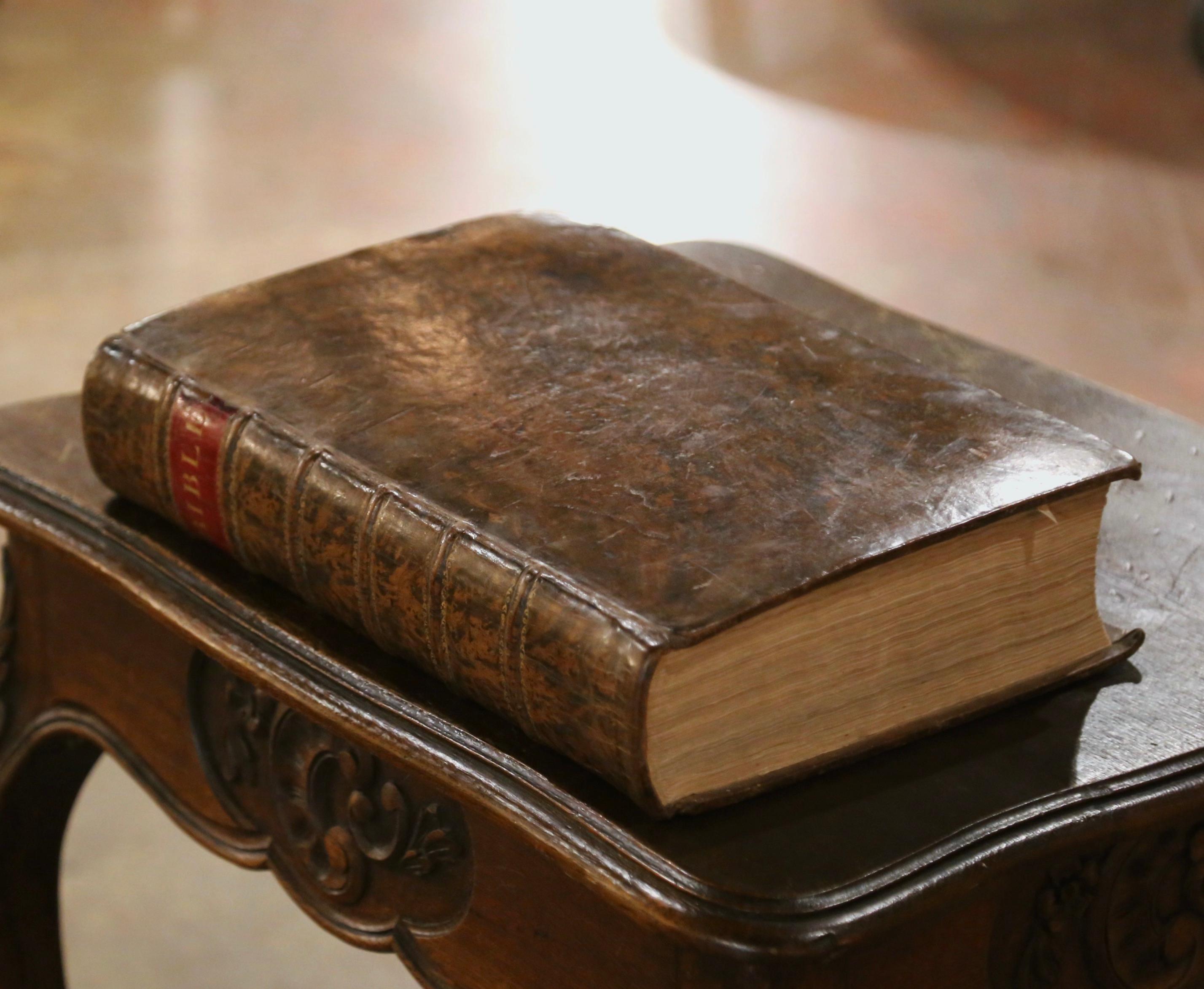 Study the word of Gog with this beautiful antique Bible. Printed in Bungay, England by Brightly and Childs circa 1814, the book showcases a sturdy leather binding with a prominent red title label marked “BIBLE” and gold tooling along the spine